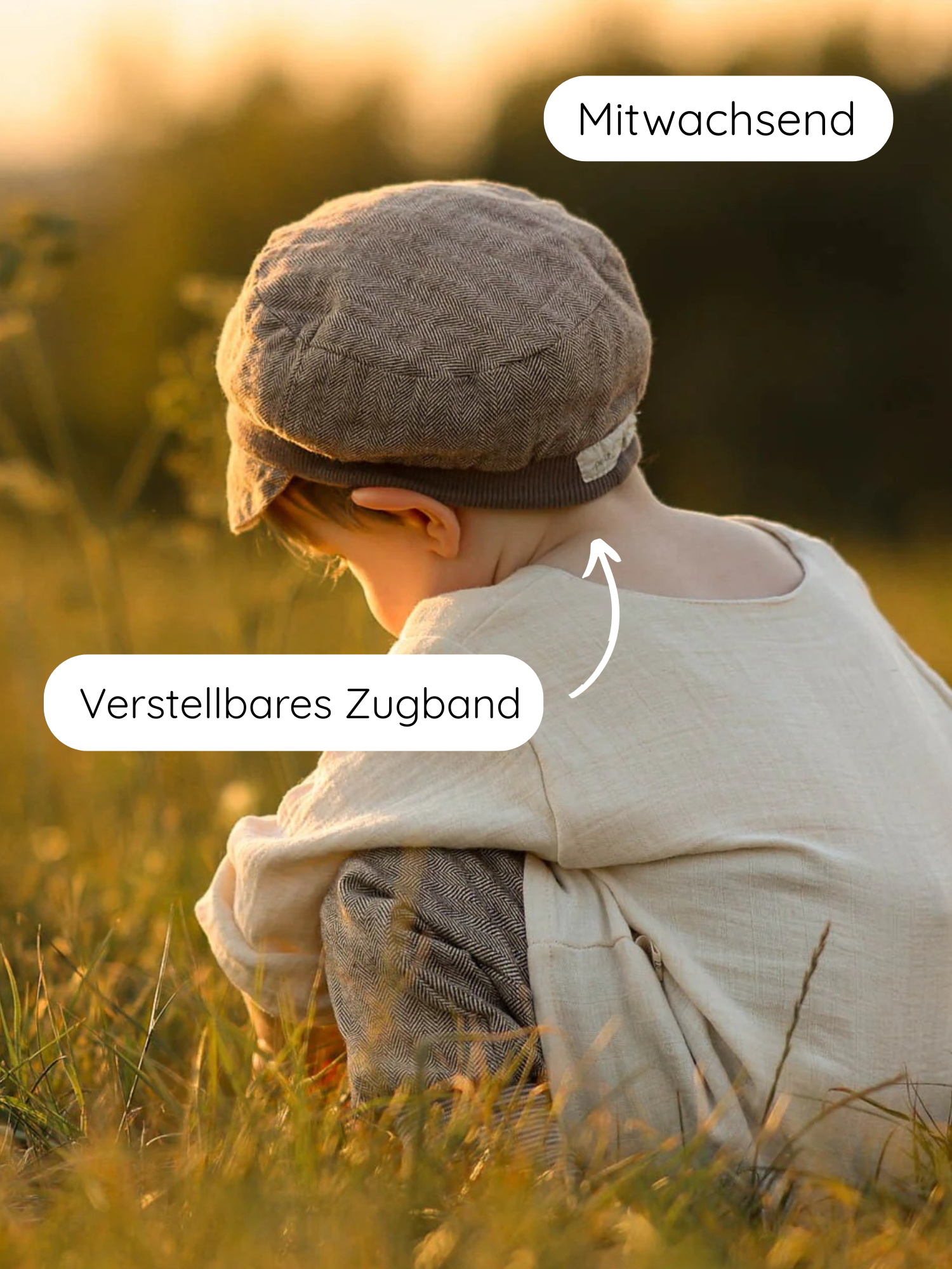 Ein Kleinkind in einem Feld trägt die Michelmütze Fischgrat Maus, eine verstellbare, mitwachsende Kappe aus weichem Fischgratstoff, mit Zugband für optimalen Sitz.