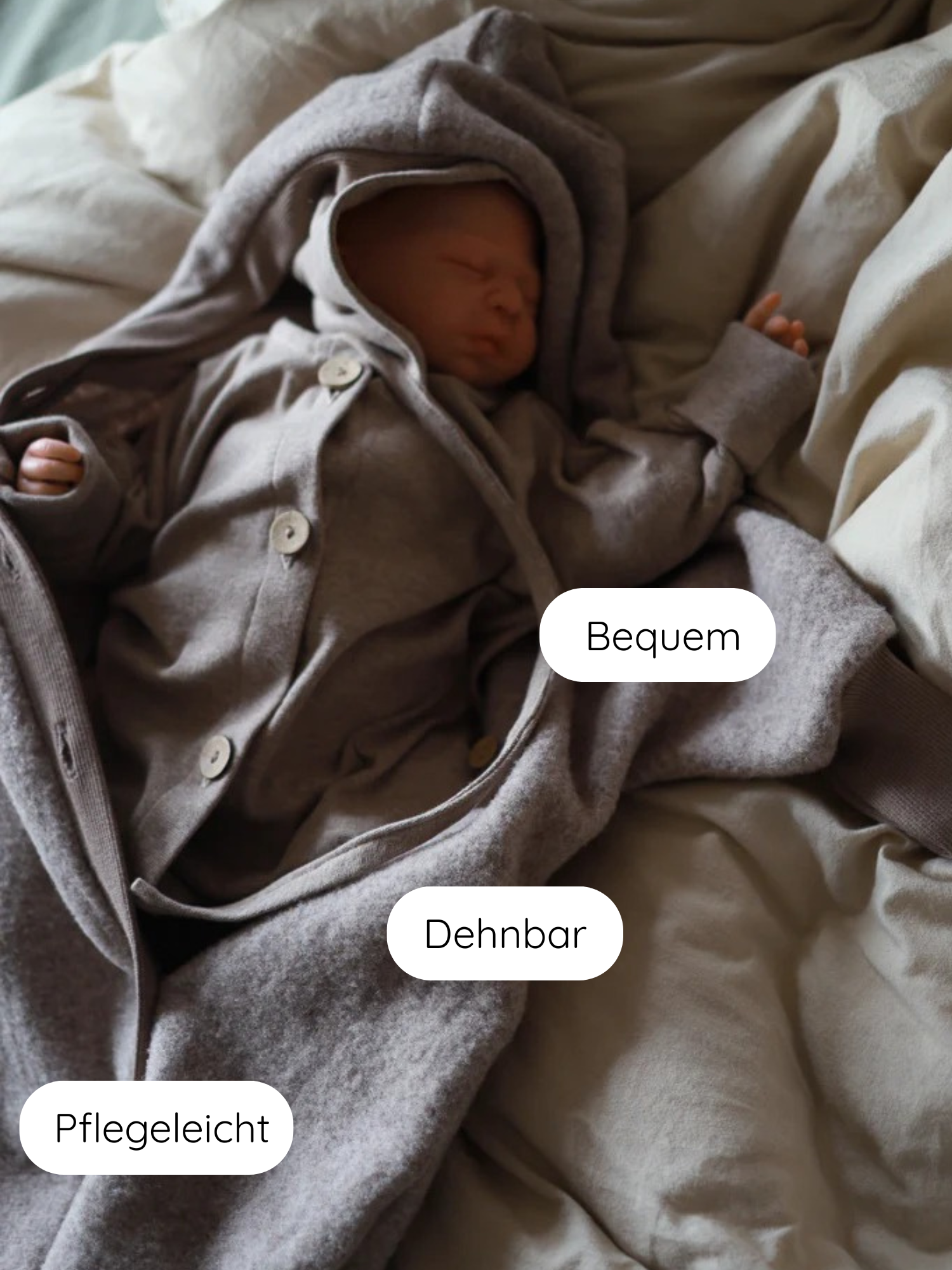 Schlafender Neugeborener in einem Mini Overall Feinstrick - Hafer Meliert. Der graue, kapuzenartige Einteiler wirkt bequem, dehnbar und pflegeleicht, perfekt für Babys beim Schlafen oder Spielen.