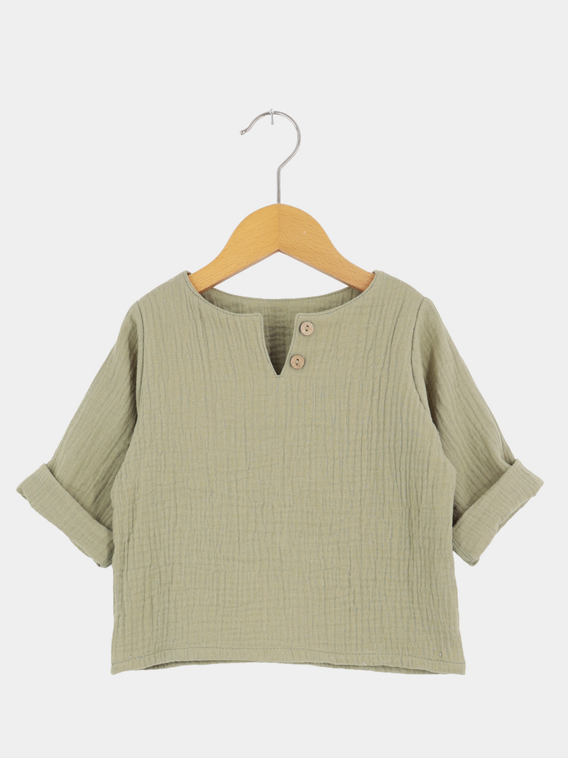 Hemdchen Musselin - Salbei, ein leichtes, langärmeliges Kinderpullover aus weichem, texturiertem Musselin. Mit V-Ausschnitt, zwei Holzknöpfen, und hochgekrempelten Ärmeln, ideal für warme Tage.