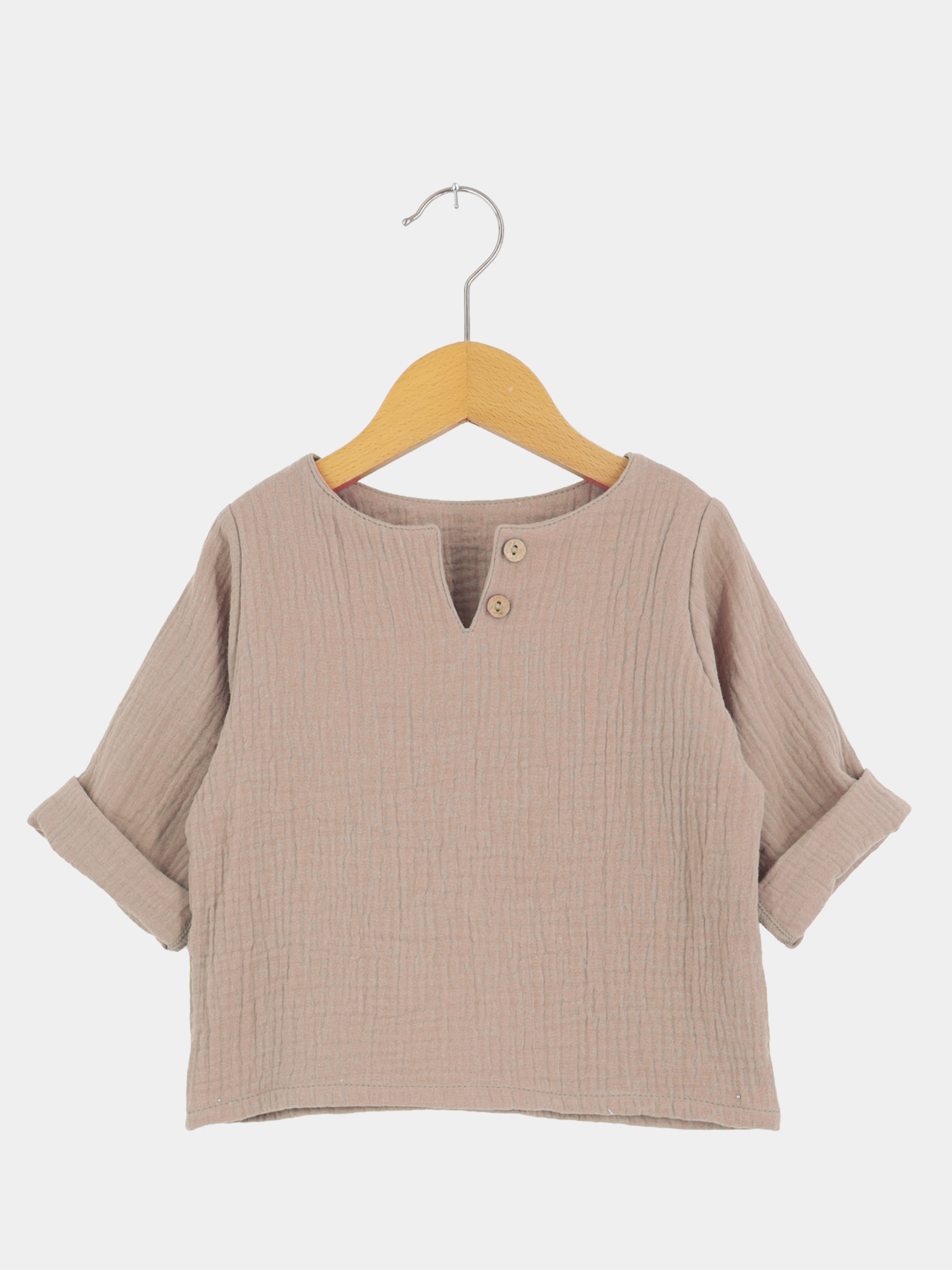 Hemdchen Musselin - Milchkaffee: Taupefarbenes, strukturiertes Langarmshirt mit V-Ausschnitt und Holzknöpfen, auf Holzkleiderbügel. Ärmel lässig aufgerollt, in weichem, atmungsaktivem Stoff für warme Tage.