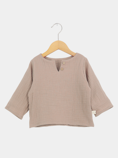 Hemdchen Musselin - Milchkaffee: Langarmshirt aus weichem, geknittertem Baumwollstoff mit V-Ausschnitt und Holzknöpfen, auf einem Holzkleiderbügel hängend, ideal für Babys und Kleinkinder.