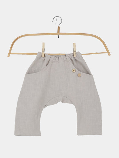 Sommerknicker Leinen - Sand: Haremshose für Babys/Kleinkinder aus leinenartigem Stoff, mit elastischem Bund, seitlichen Taschen, zwei Holzköpfen, auf einem Bambusbügel präsentiert. Ideal für Bewegungsfreiheit und Komfort.