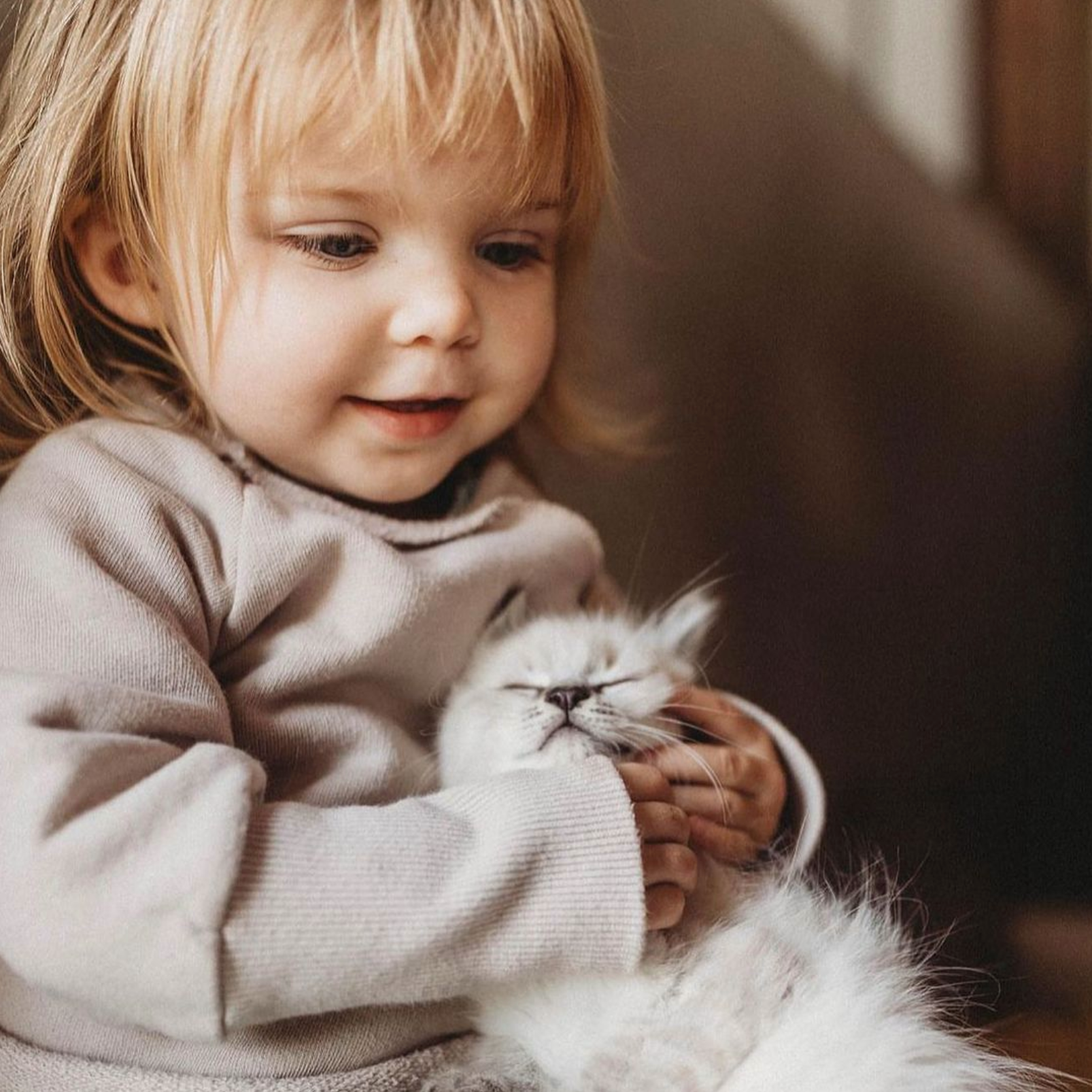Kind hat Katze auf dem Arm. Trägt Schlüttli aus Bio-Baumwolle Sand. Nachhaltige Kinderkleidung in Berlin genäht.