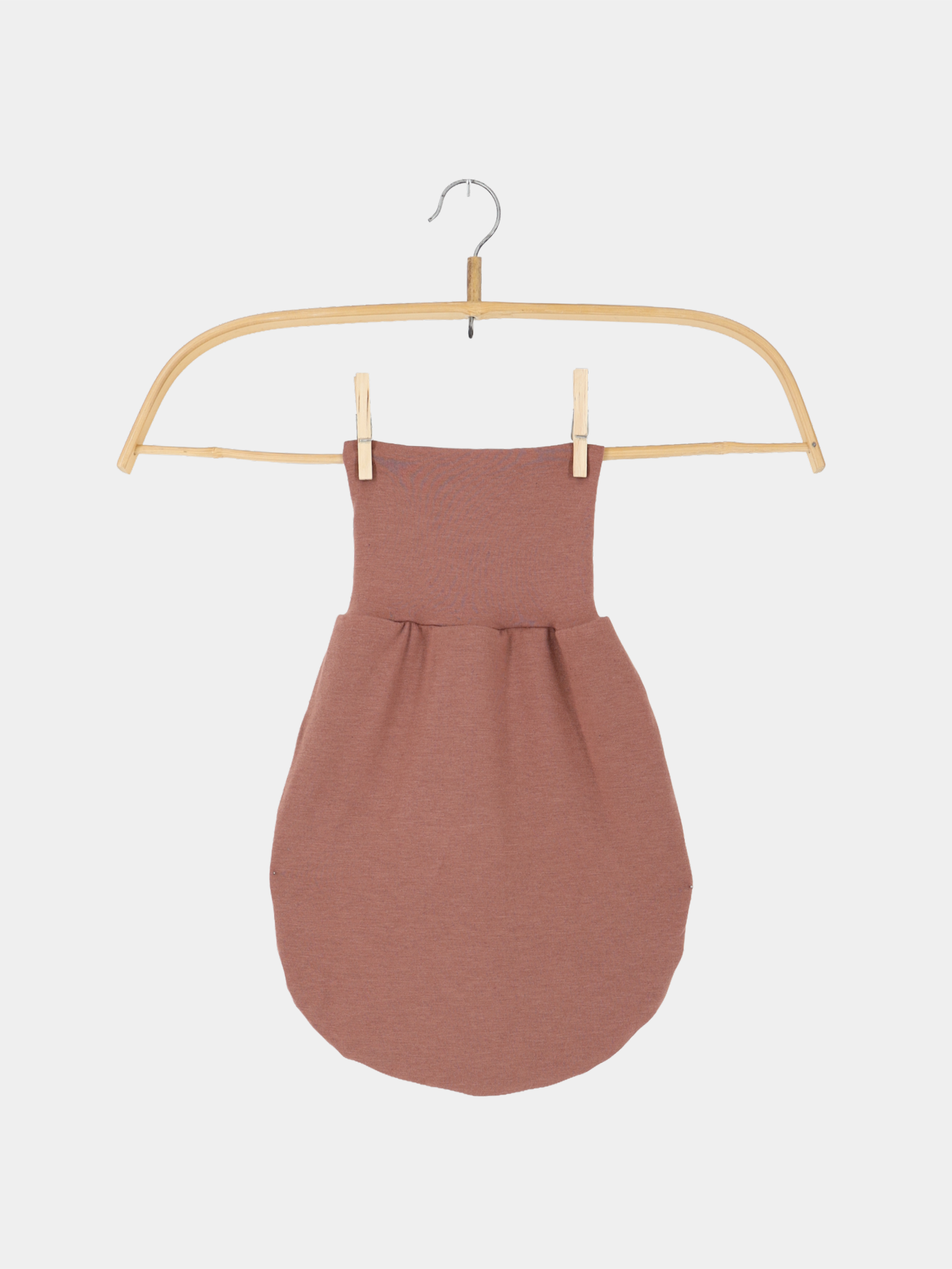 Baby Strampel- und Pucksack Kaschmir-Mix - Zimt, ein ärmelloser Schlafsack in rötlich-braunem Strick, hängt an einem schlanken Holzkleiderbügel, befestigt mit zwei Wäscheklammern.