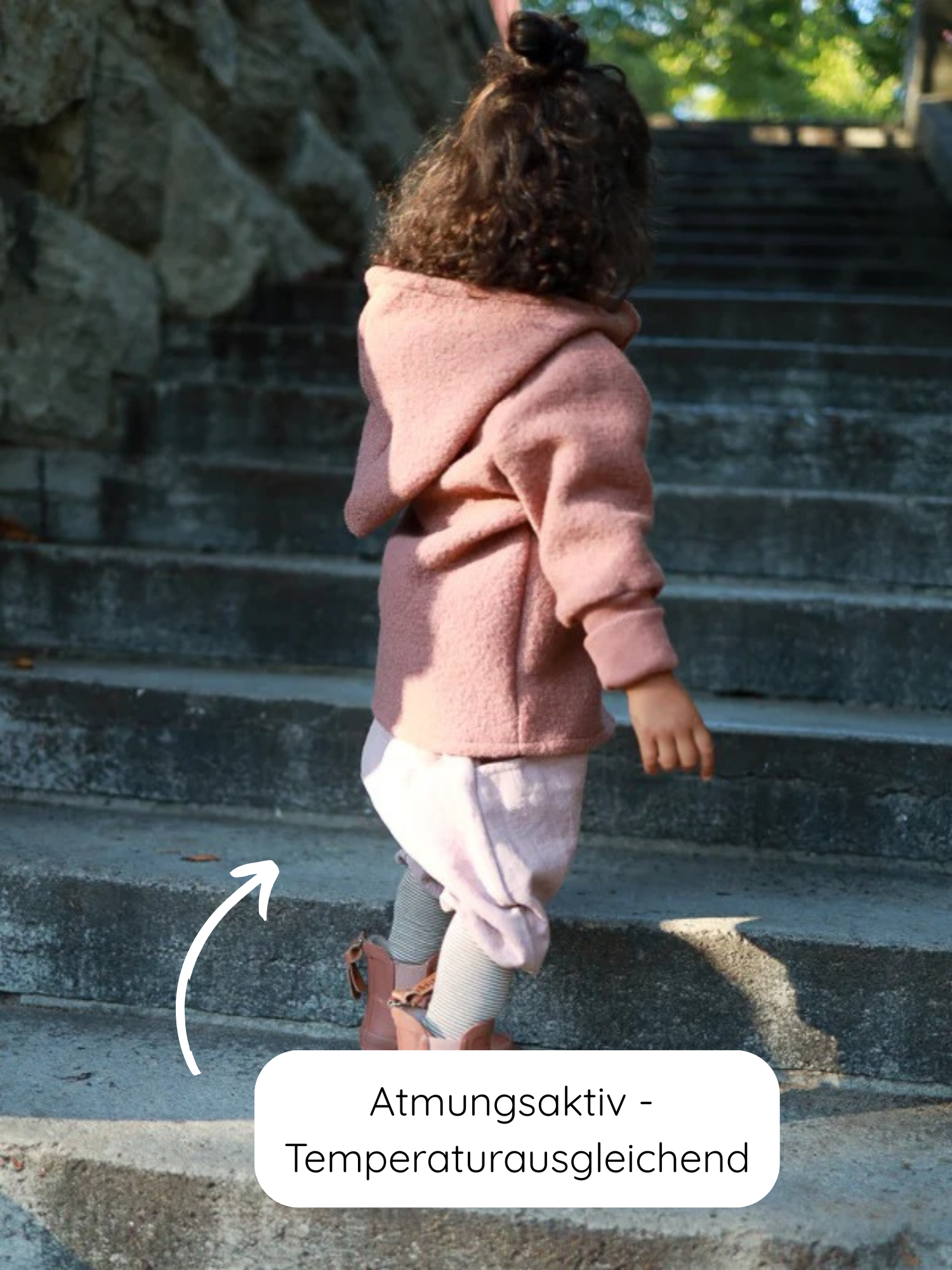 Ein Kind klettert Steinstufen hinauf, trägt die Wichteljacke Wollwalk - Zimt. Die atmungsaktive, temperaturregulierende Wolljacke bietet Bewegungsfreiheit und ist ideal für Herbst, Frühling und Winter.