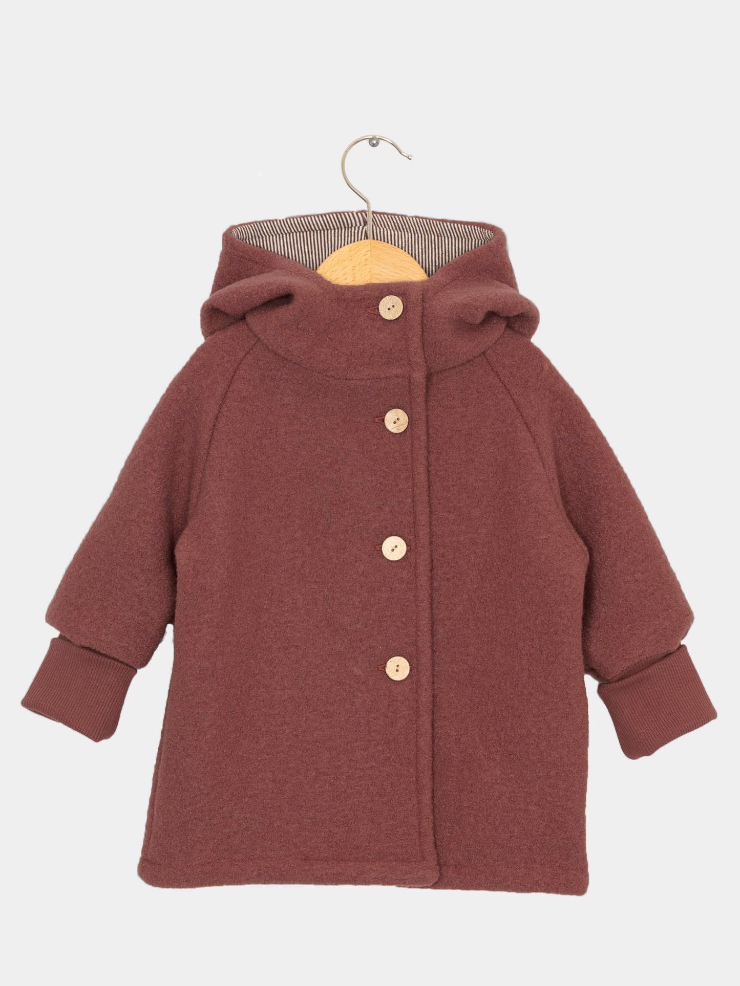 Wichteljacke Wollwalk - Ziegel: Kinder-Hoodie-Mantel aus weichem Wollstoff, mit geräumiger Kapuze, vier Holzknöpfen, breiten Rippbündchen und einem geraden Schnitt auf Holzbügel, ideal für Herbst bis Frühling.