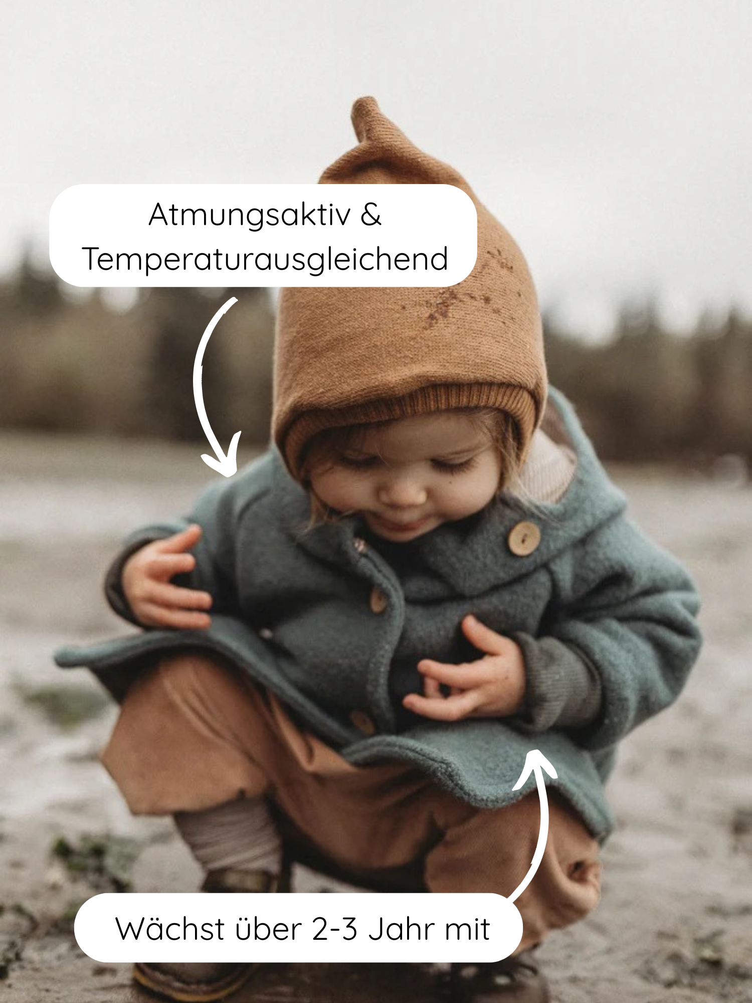 Kleinkind hockt im Freien, trägt die Wichteljacke Wollwalk - Taube in muted-grün mit Knöpfen und brauner Strickmütze. Pfeile betonen atmungsaktive, temperaturregulierende Eigenschaften und mitwachsenden Schnitt der Jacke.