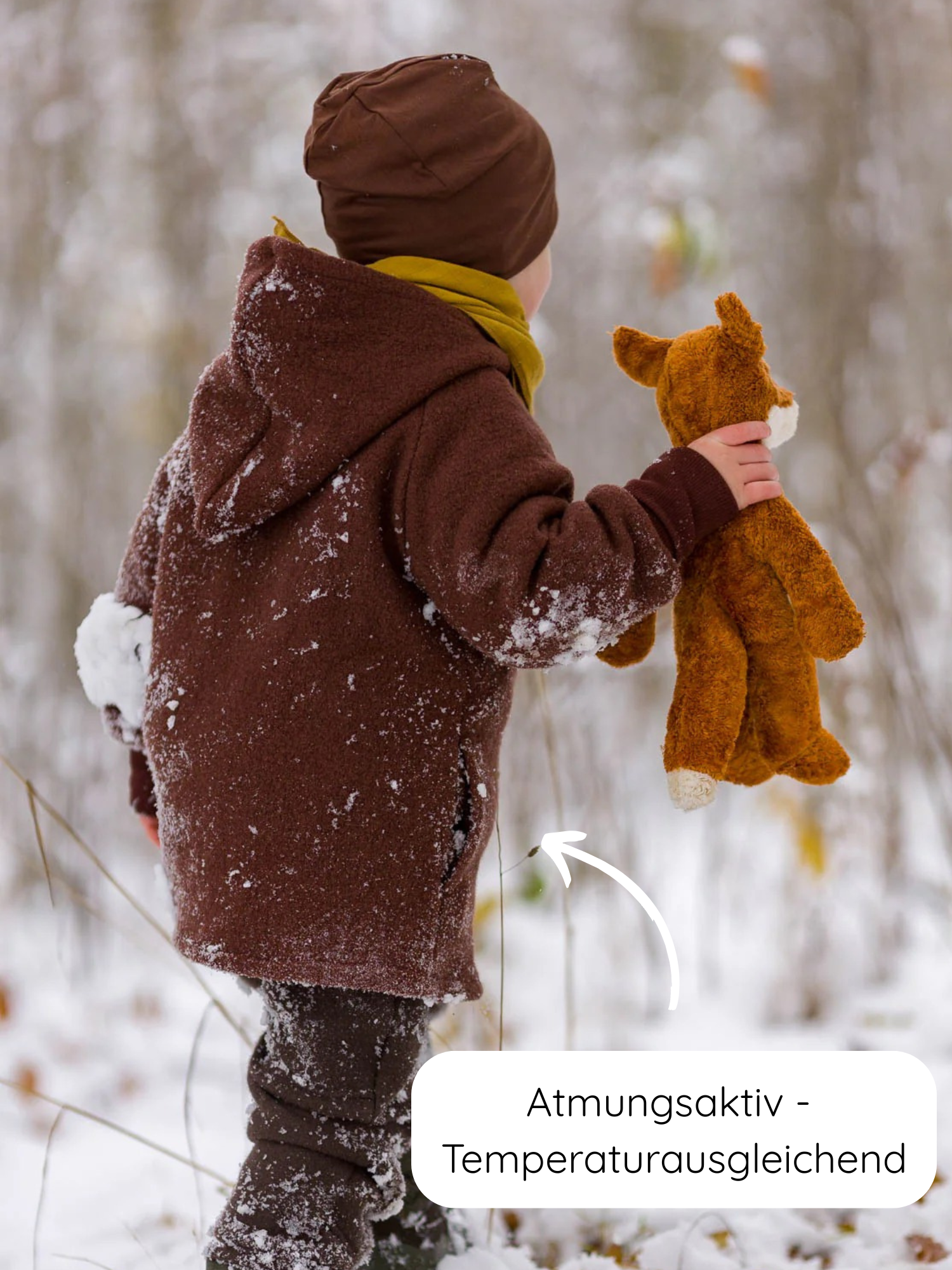 Ein Kind im Schnee trägt die Wichteljacke Wollwalk - Schoko, mit Bio-Jersey-Futter. Die Jacke ist atmungsaktiv und temperaturausgleichend, perfekt für Herbst, Winter und Frühling.