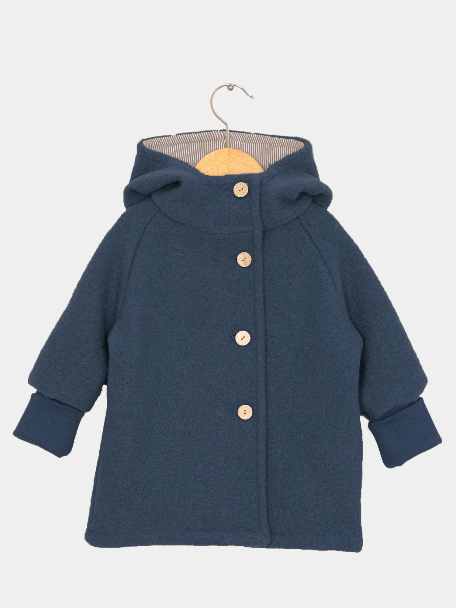 Wichteljacke Wollwalk - Marine: Navy-blauer Mantel mit Kapuze, A-Linien-Schnitt, vier runden Holzknöpfen, gerippten Bündchen, gestreiftem Innenfutter. Hängend an Holzkleiderbügel, ideal für kühle Jahreszeiten.