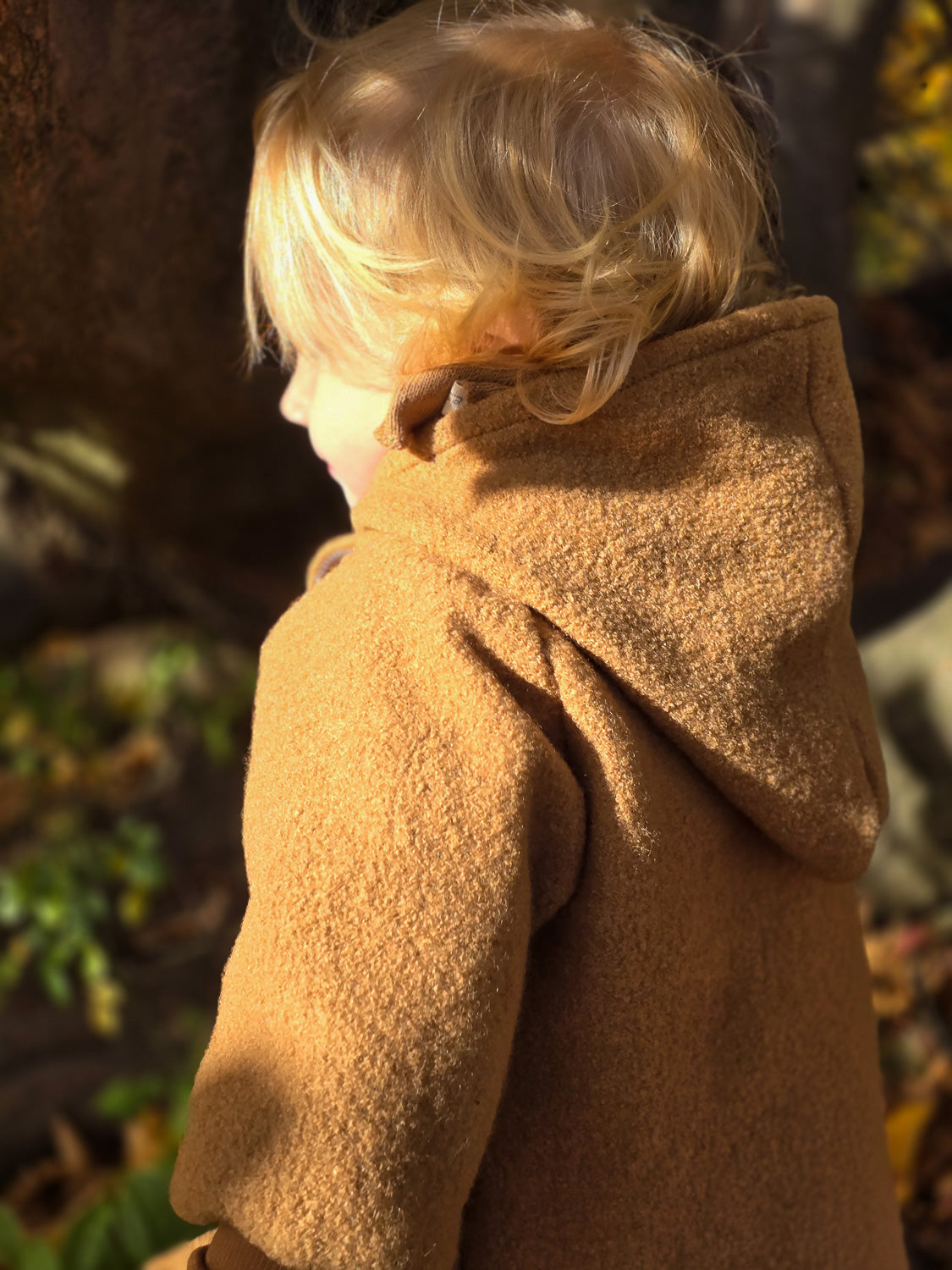Kind trägt die Wichteljacke Wollwalk - Kamel, mit großer Bewegungsfreiheit und temperaturregulierendem Material, ideal für Herbst bis Winter, mit Bio-Jersey-Futter und krempelbaren Bündchen, unisex Design. nachhaltige Wollwalk Jacke für Kinder