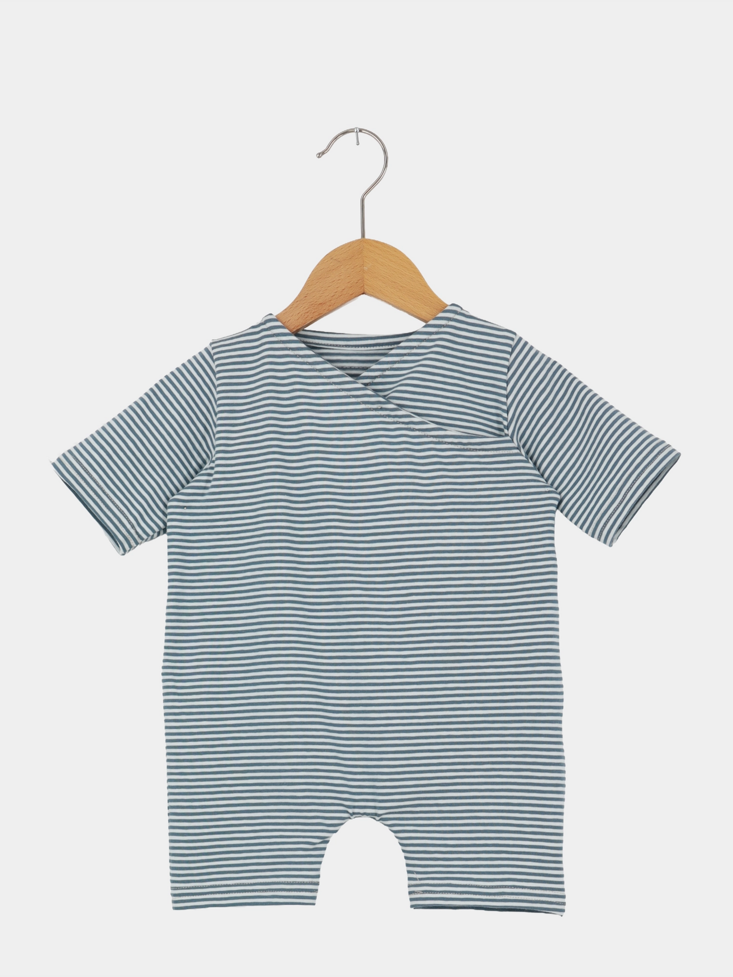 Wickel Overall Baumwolle - Ringel Taube: Ein kurzärmeliger Baby-Body mit schmalen blau-weißen Streifen, aus doppellagigem Bio-Musselin, hängend an einem Holzkleiderbügel, ideal für warme Tage.