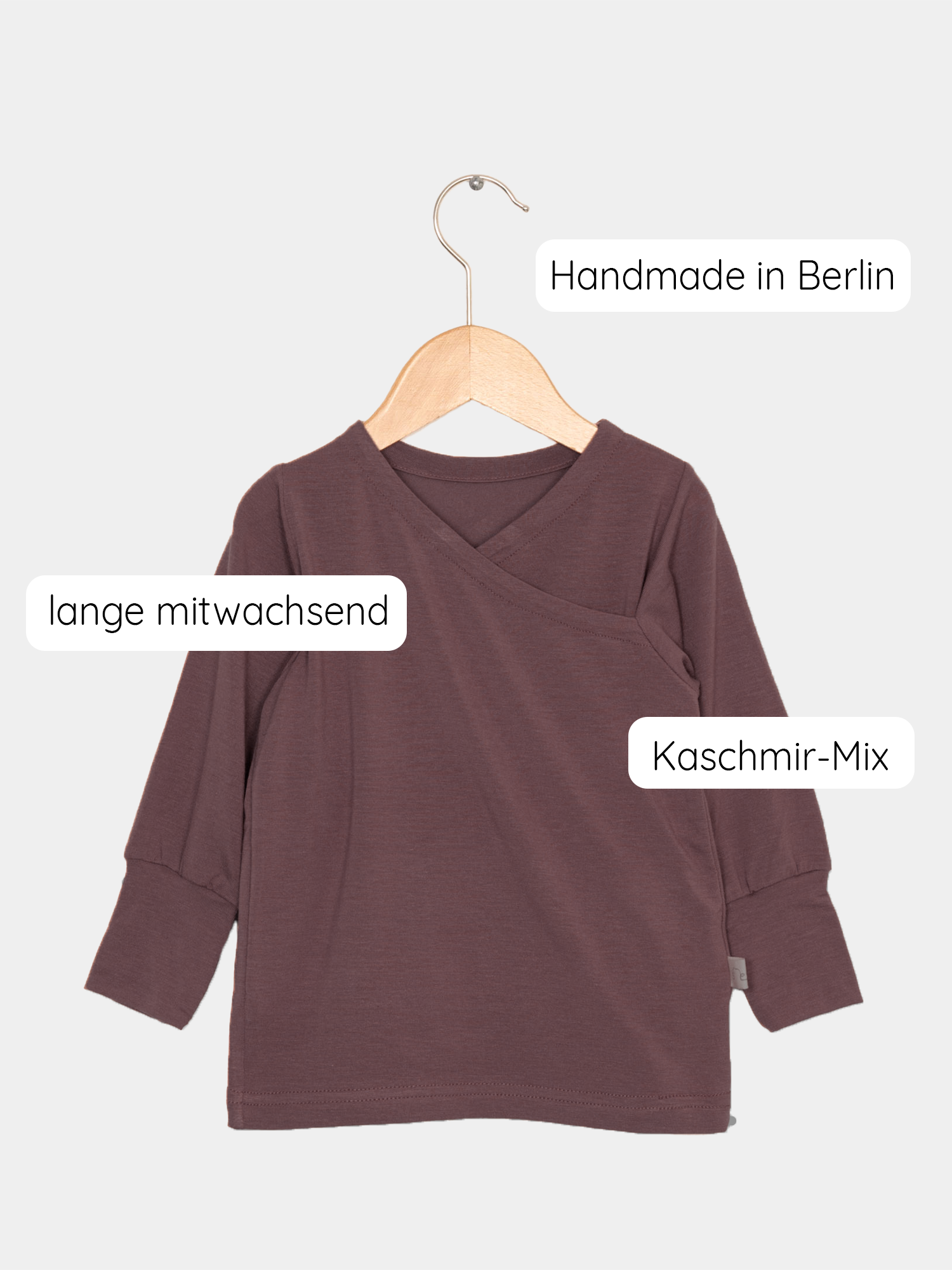 Wickelshirt aus Kaschmir-Mix - Malve auf einem Holzschwinger, langärmelig, mit feinen Nähten und krempelbaren Bündchen, präsentiert die weiche, elastische Textur, ideal als Shirt oder Unterhemd.
