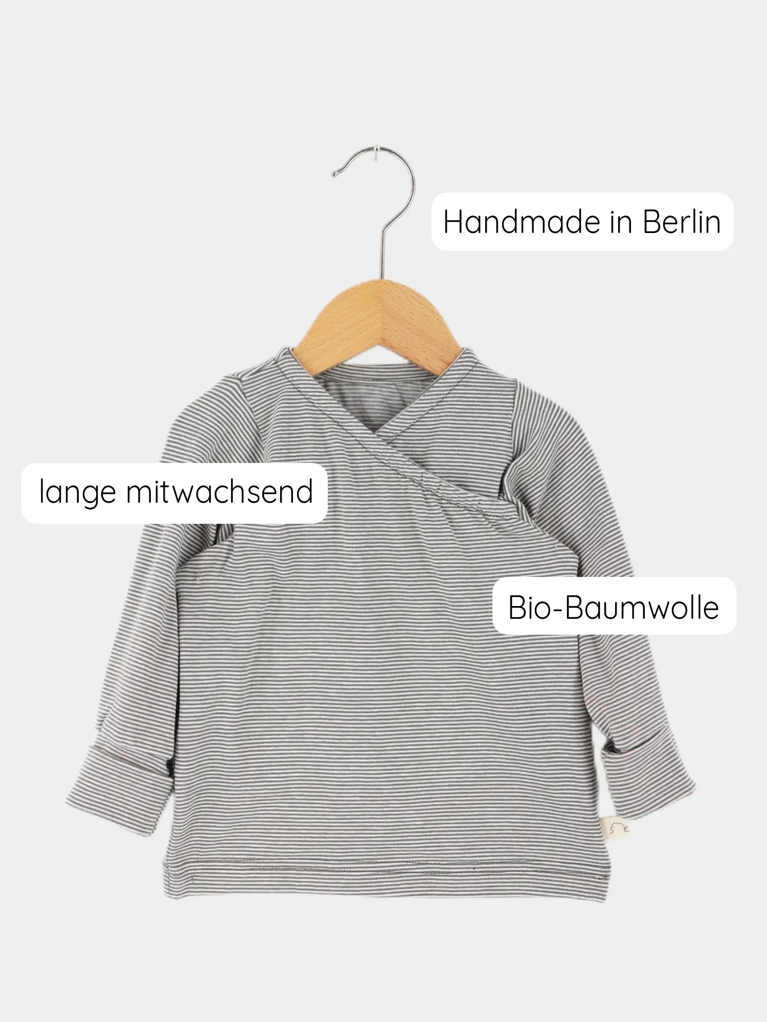 Wickelshirt aus Bio-Baumwolle - Ringel Maus: Langärmeliges Shirt in grau-weißen Streifen, auf Holzkleiderbügel. Handgemacht in Berlin, mitwachsend, aus weicher Bio-Baumwolle. Ideal für Babys, leicht anzuziehen.