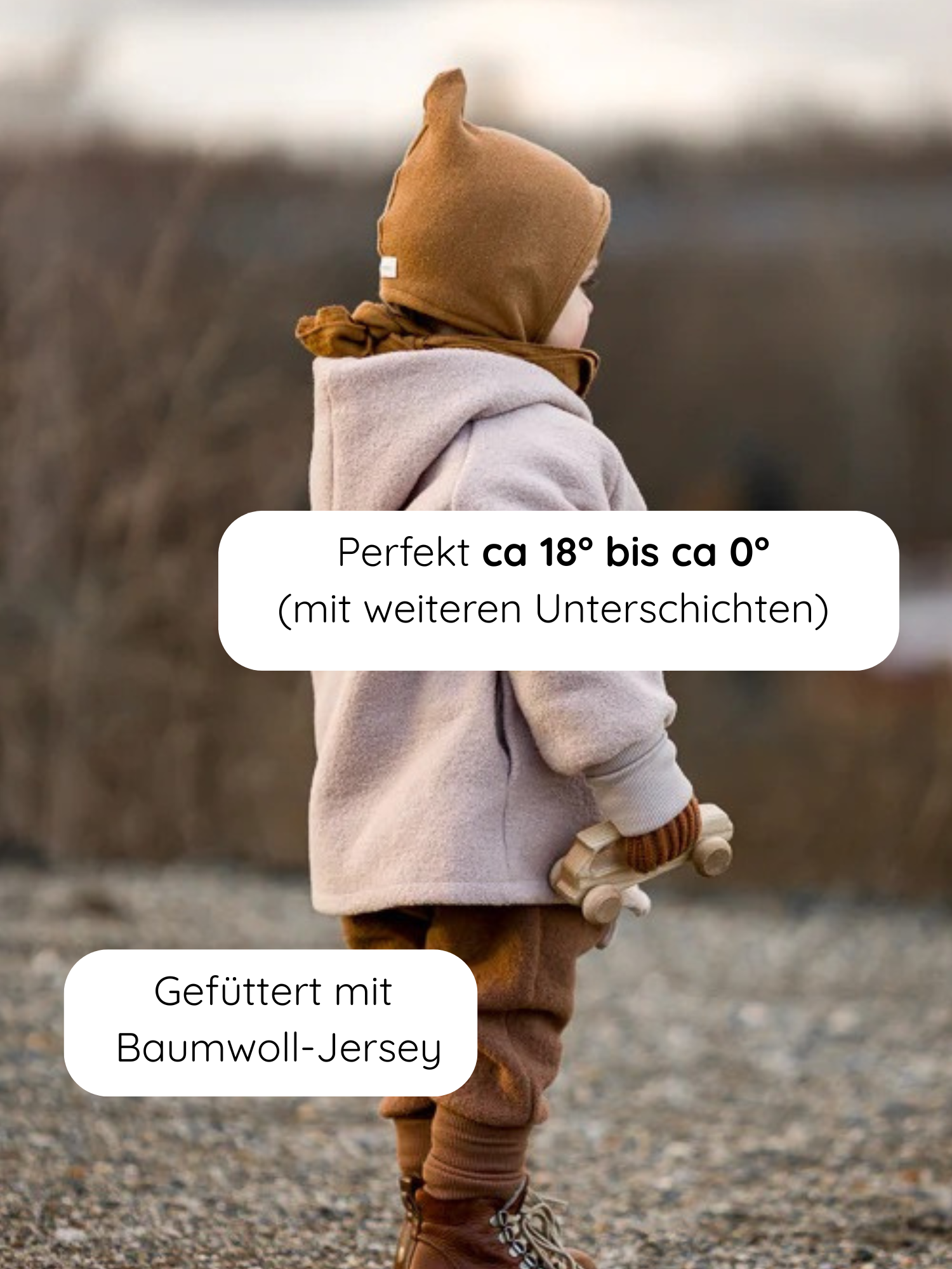 Ein Kind trägt die Wichteljacke Wollwalk - Sand, eine beige Jacke aus Wollwalk mit Jersey-Futter, kombiniert mit rustbraunen Hosen und braunen Lederstiefeln, und hält ein Holzauto.