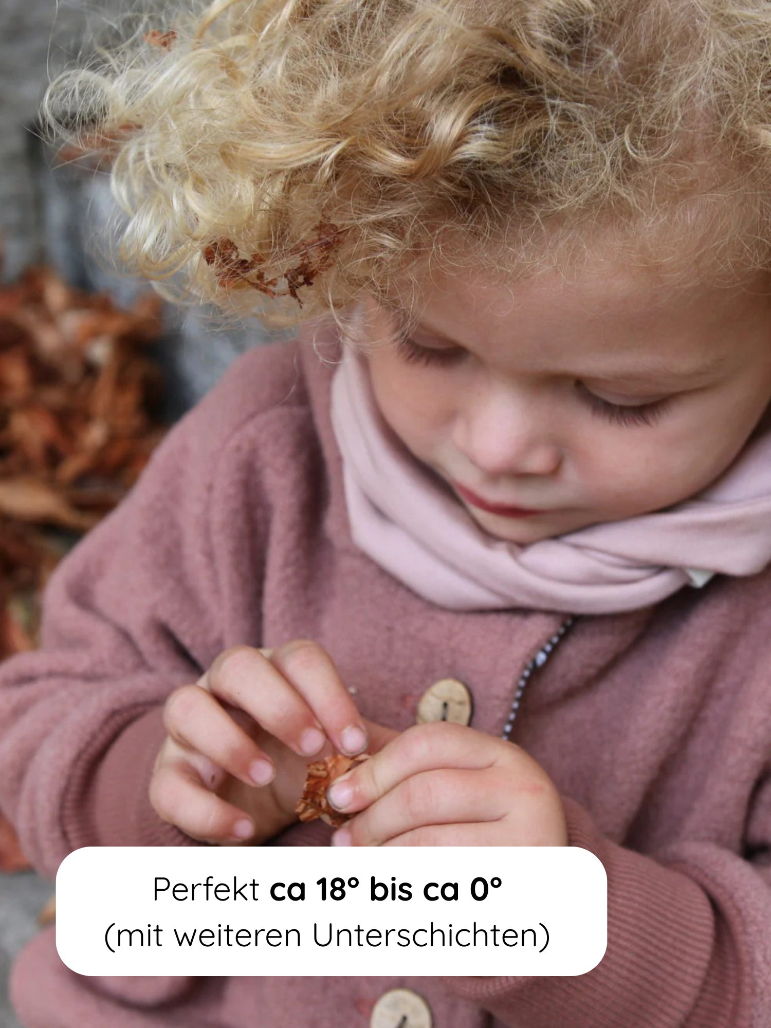 Kleines Kind in Wollwalk-Jacke Wichteljacke - Zimt, sitzt zwischen Herbstblättern, untersucht ein trockenes Blatt. Text erklärt, dass die Jacke perfekt für Temperaturen von 18°C bis 0°C geeignet ist.