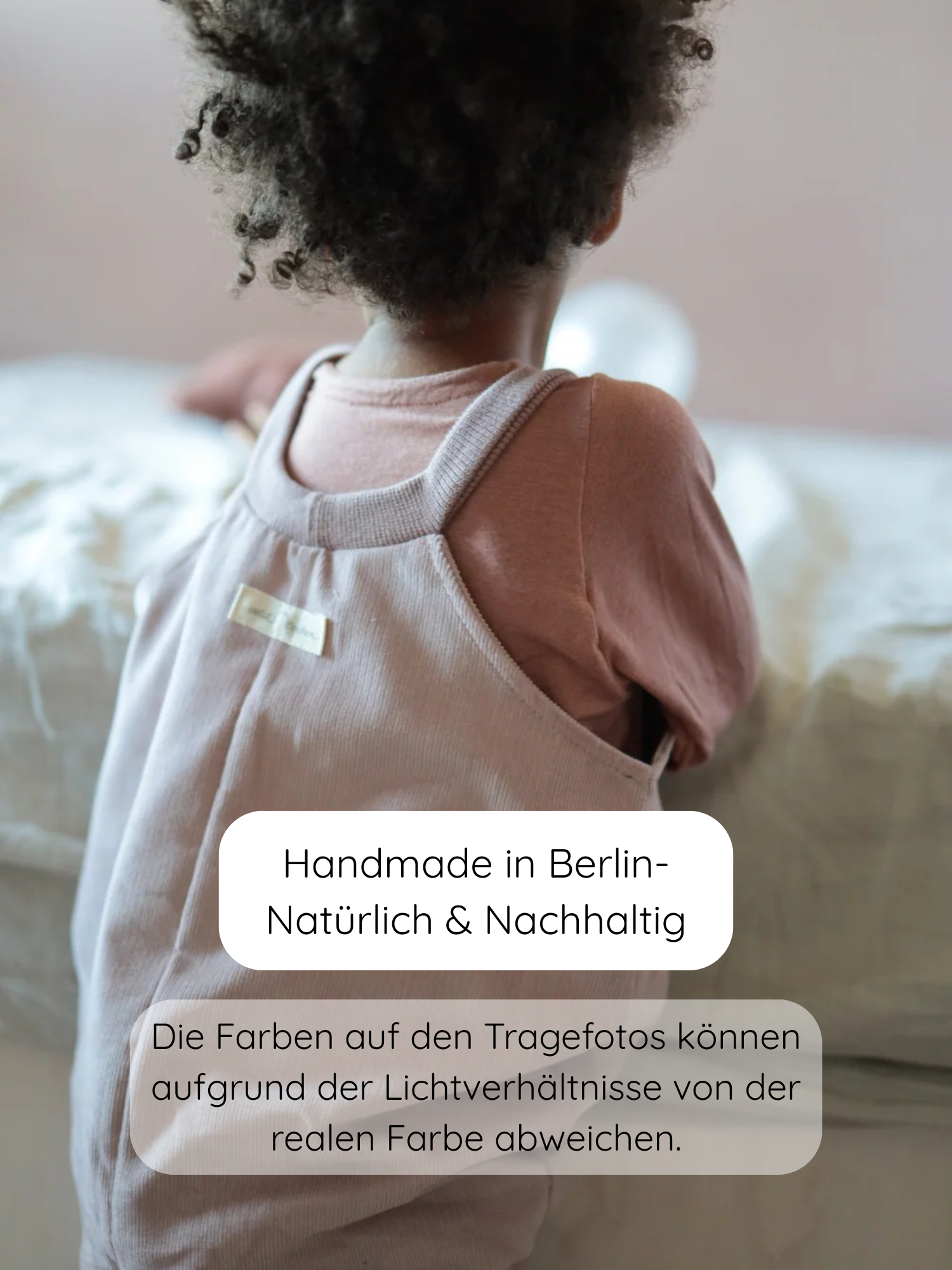 Ein kleines Kind lehnt an einem Bett, trägt ein Wickelshirt aus Kaschmir-Mix - Zimt. Das weiche, ärmellose Einteiler-Design ist handgefertigt in Berlin, natürlich und nachhaltig.