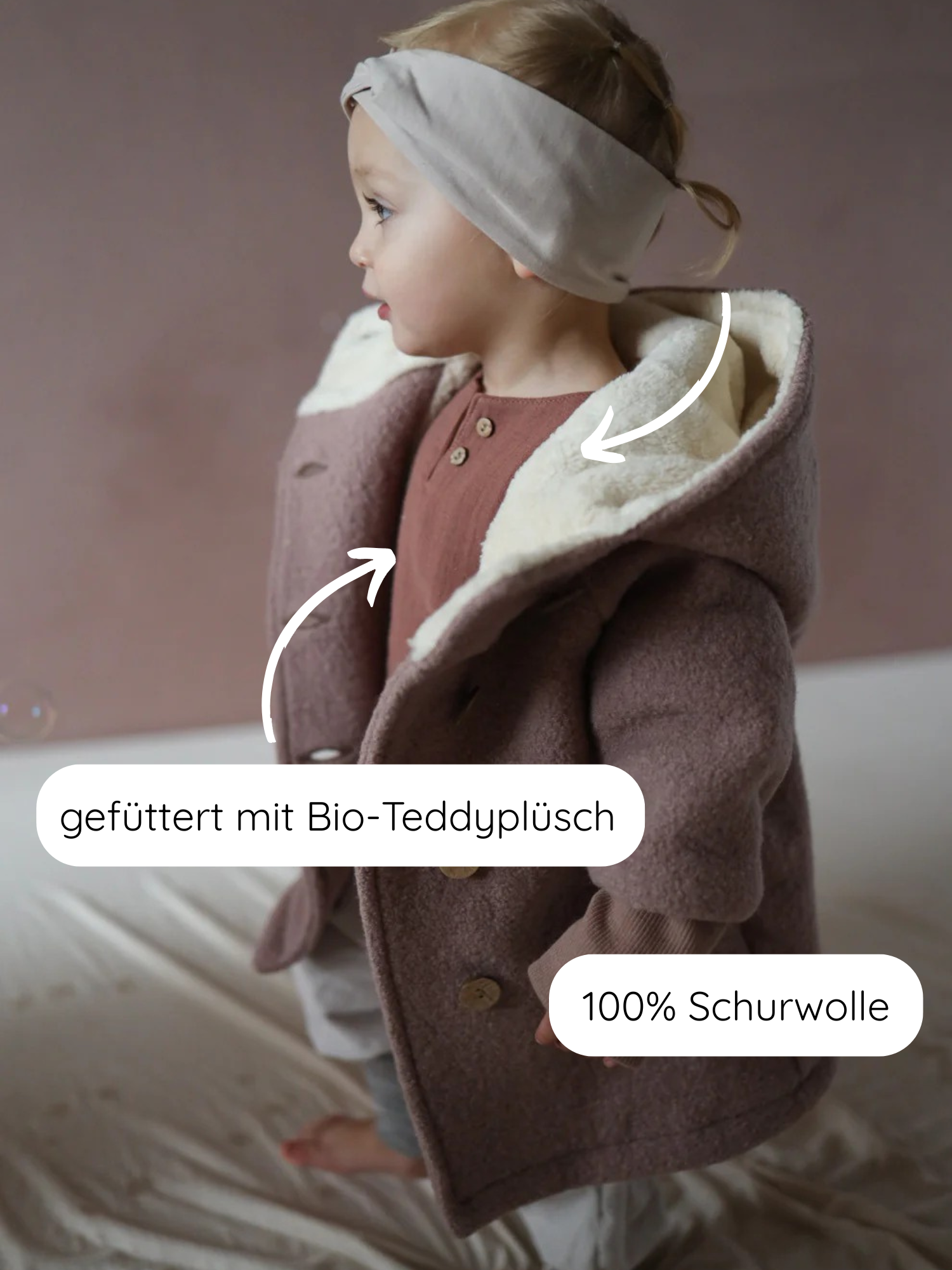 Kleinkind trägt Winter Wichteljacke Wollwalk - Puder: doppelt geknöpfter Mantel aus 100% Schurwolle, gefüttert mit Bio-Teddyplüsch. Charakteristische Kapuze, breiten Krempelbündchen, ideal für kalte Tage.