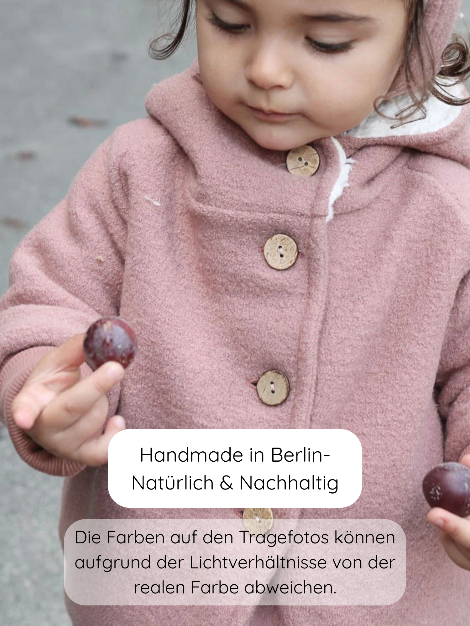 Nahaufnahme eines Kindes in einer Winter Wichteljacke Wollwalk - Puder, mit hölzernen Knöpfen. Das Kind hält zwei dunkellila Früchte, vermutlich Pflaumen, in den Händen. Text: Handmade in Berlin – Natürlich & Nachhaltig.
