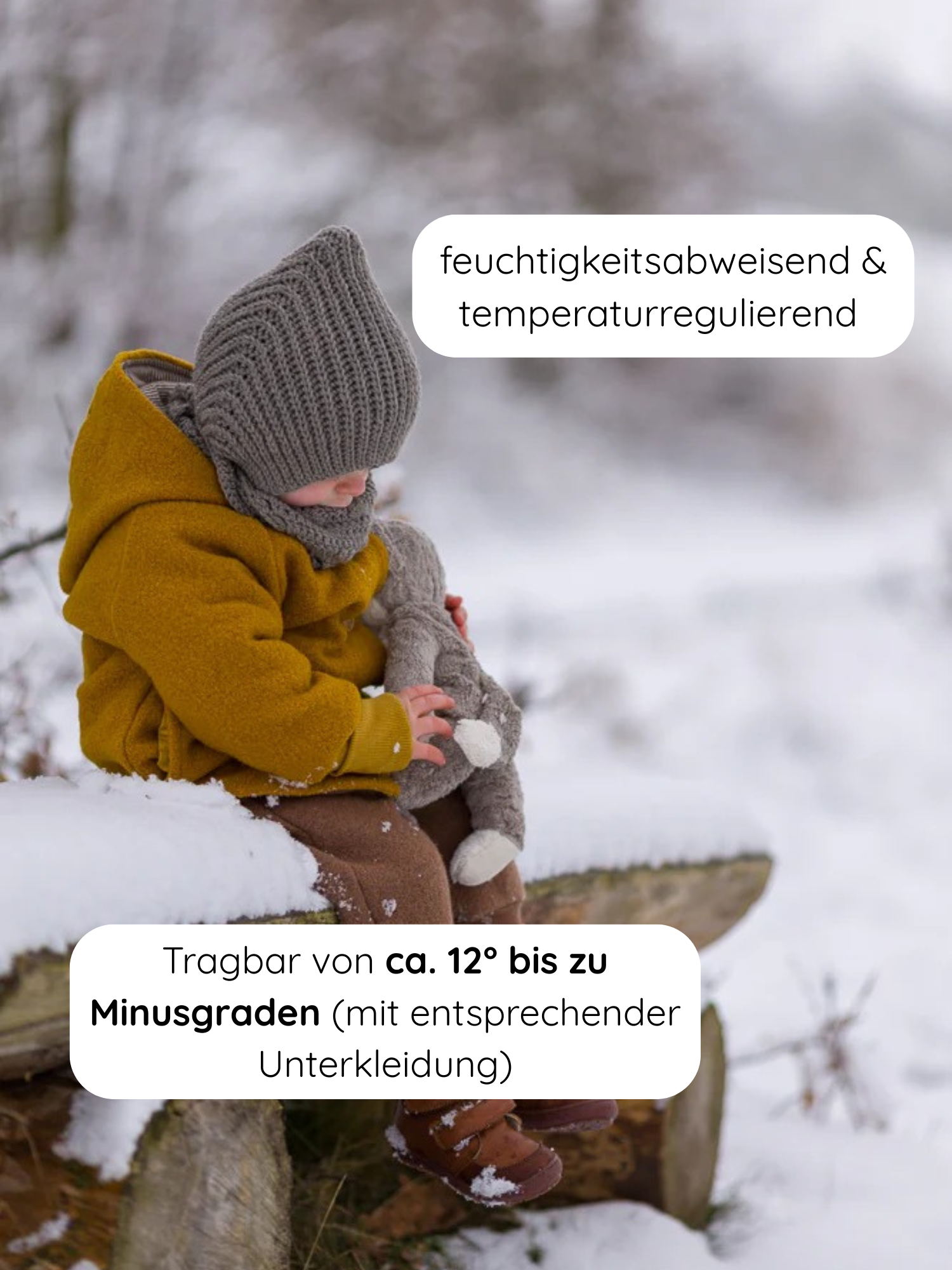 Kind im Schnee, trägt Winter Wichteljacke Wollwalk mit Teddyfutter - Honig, mit Wichtelkapuze und Krempelbündchen. Hält graues Kuscheltier, sitzt auf Baumstamm. Jacke ist feuchtigkeitsabweisend und temperaturregulierend.