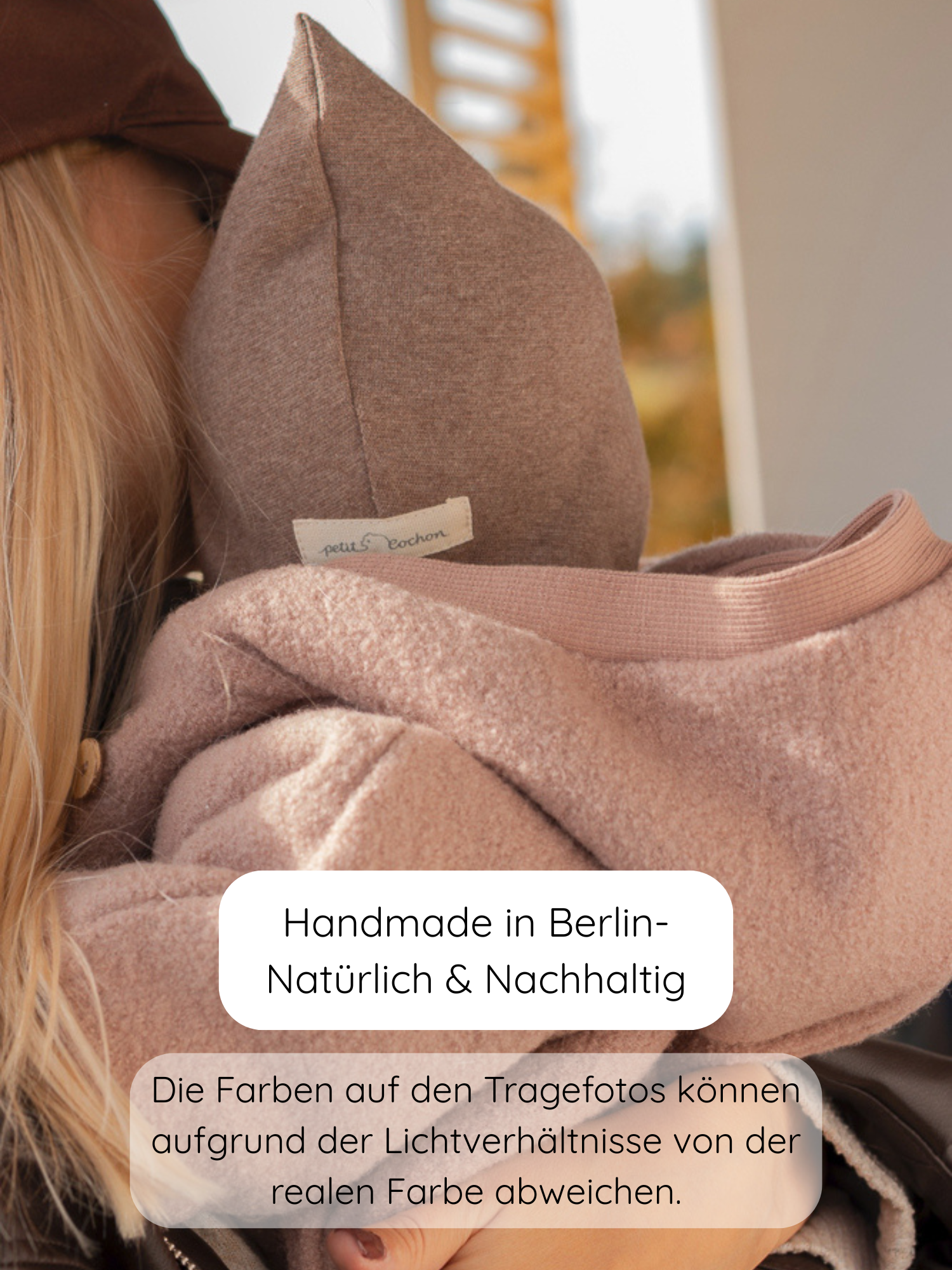 Nahaufnahme eines Kindes in einem weichen Tragesling, das den Winter Wollwalk Overall mit Teddyfutter - Puder trägt, ideal für kalte Tage, handgefertigt in Berlin aus nachhaltigen Materialien.