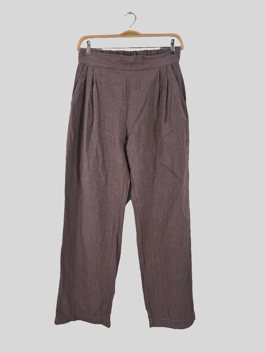 Bundfalten Hose Leinen Erde Gr. M, präsentiert auf einem Holzkleiderbügel, zeigt sich mit eleganten Falten und weitem Schnitt, ideal für einen stilvollen, komfortablen Look. Zustand: sehr gut.