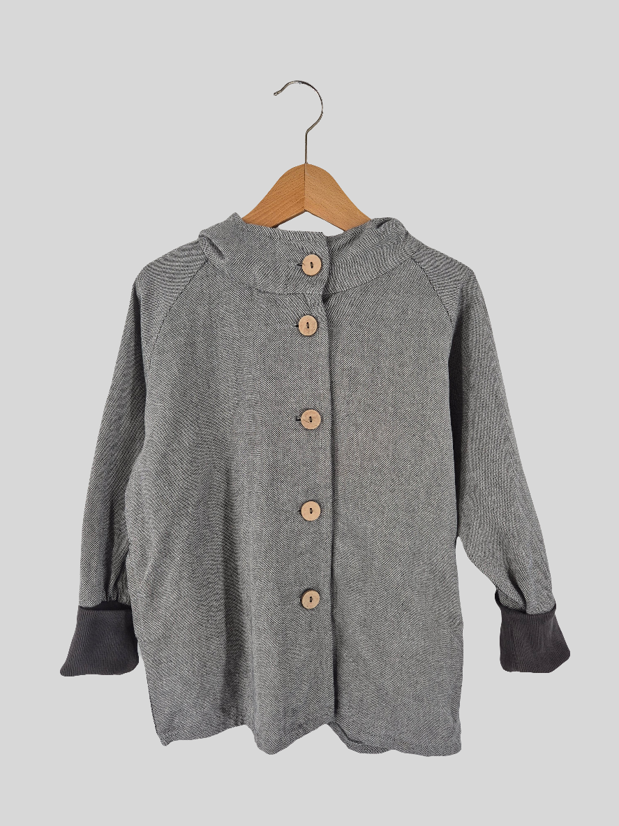 Wichteljacke Kreuzköper Maus Gr. 4/5Y: Leichte graue Jacke im Fischgrätmuster mit kleinem Stehkragen, langen Raglanärmeln und dunklen, gerippten Bündchen, verziert mit fünf runden Holzknöpfen. Zustand: sehr gut.