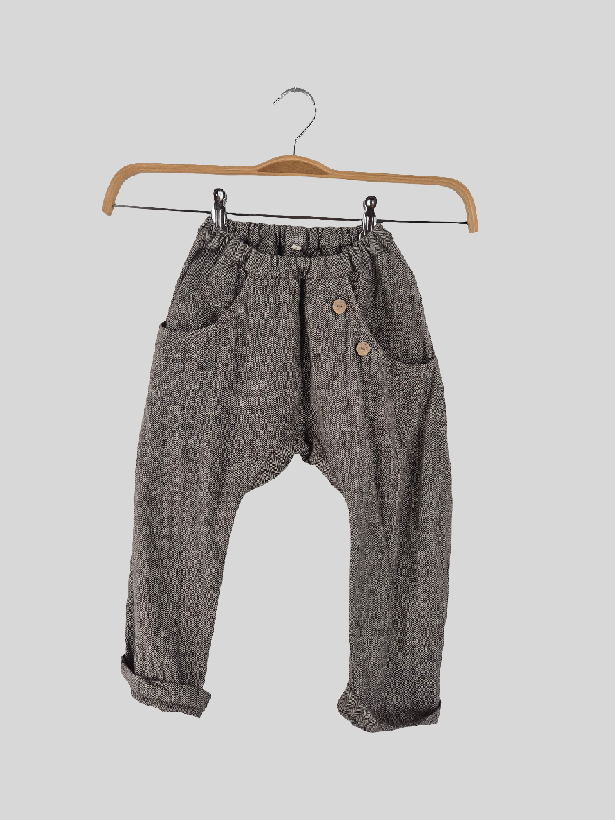 Sommerknicker Fischgrat pur Gr. 4/5Y, graue Hose mit Fischgrätenmuster, elastischem Bund, zwei Fronttaschen, zwei dekorativen Holzknöpfen seitlich und hochgekrempelten Hosenbeinen, hängend an einem Holzkleiderbügel. Zustand: sehr gut.