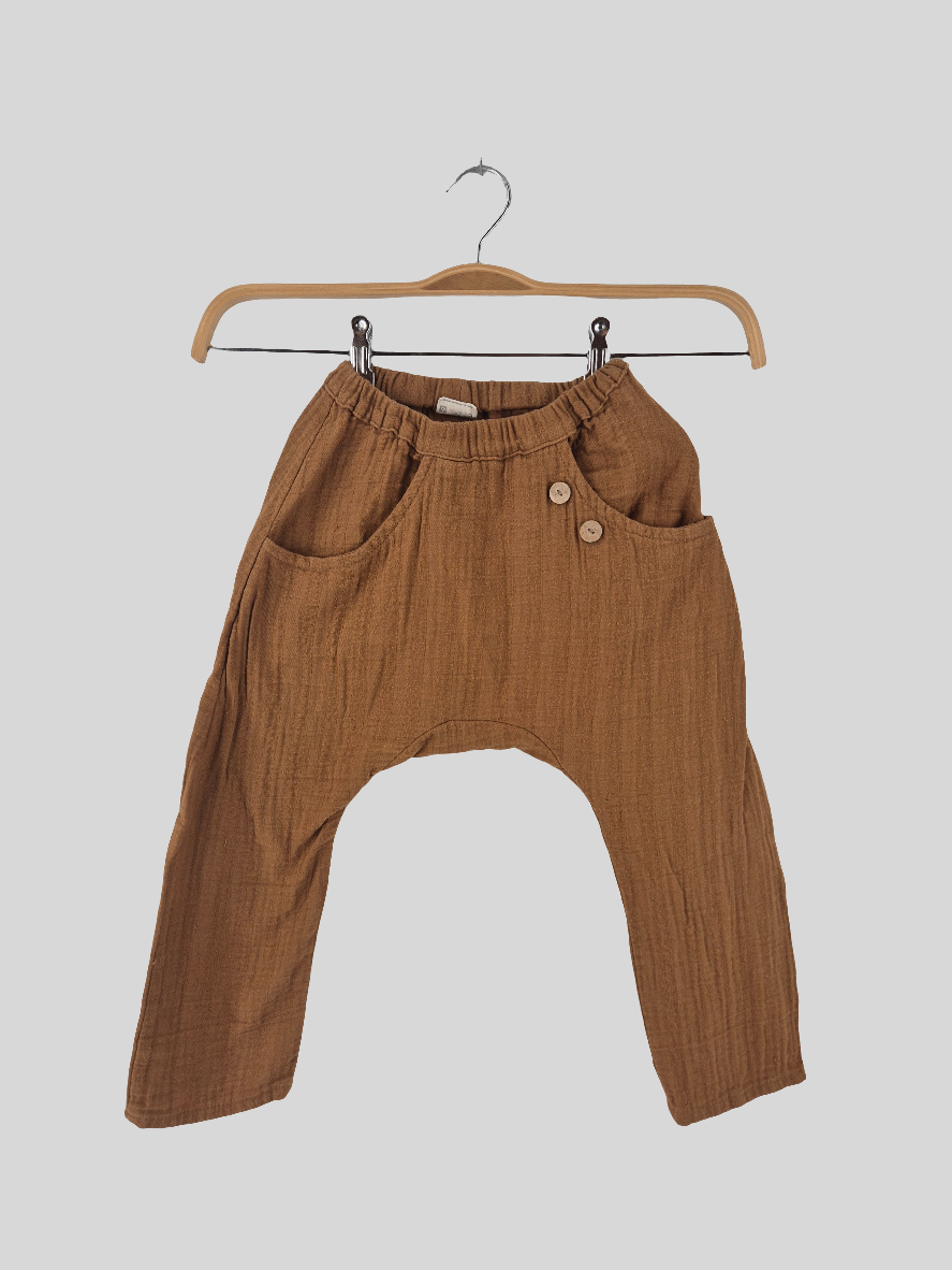 Sommerknicker Bio Musselin Sahara Gr. 3Y: Kinderhose in warmem Braun, aus leichtem, geknittertem Stoff. Lockerer Harem-Schnitt, elastischer Bund, Hüfttaschen, zwei Holzknöpfe, kleines Loch am Knie.