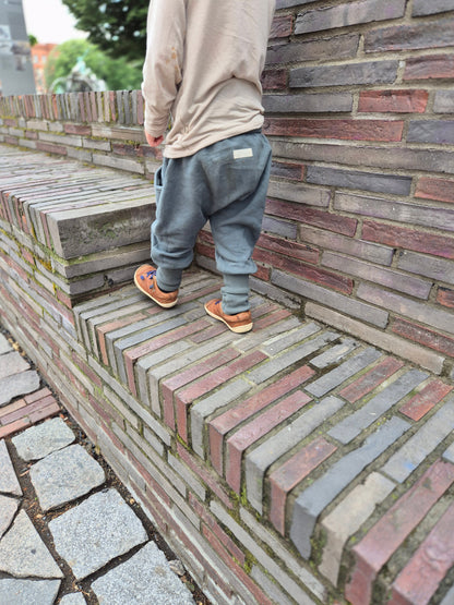 Kind trägt eine bequeme petit cochon Knickerbocker Hose aus Bio-Sweat in Schoko beim Treppensteigen im Freien.