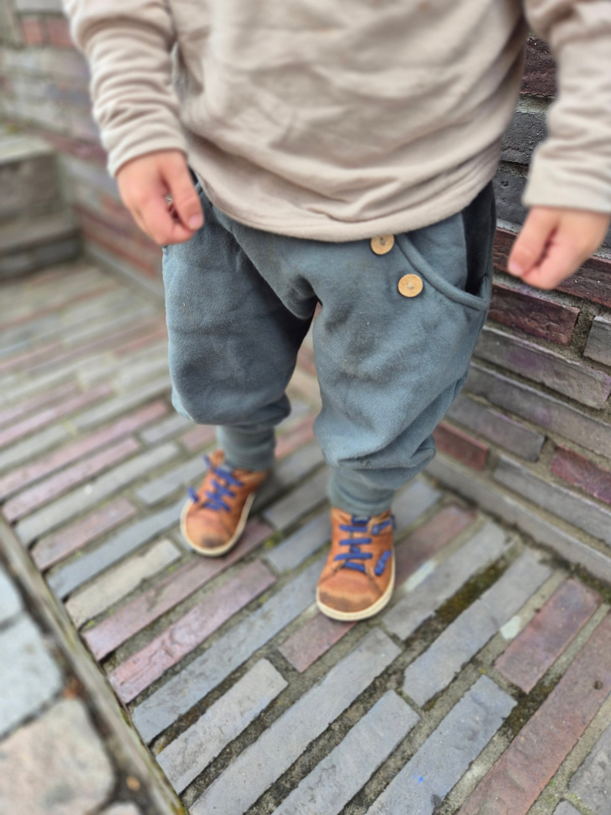 petit cochon Knickerbocker Hose aus schokobraunem Bio-Sweat mit Kokosknöpfen an einem Kind im Freien