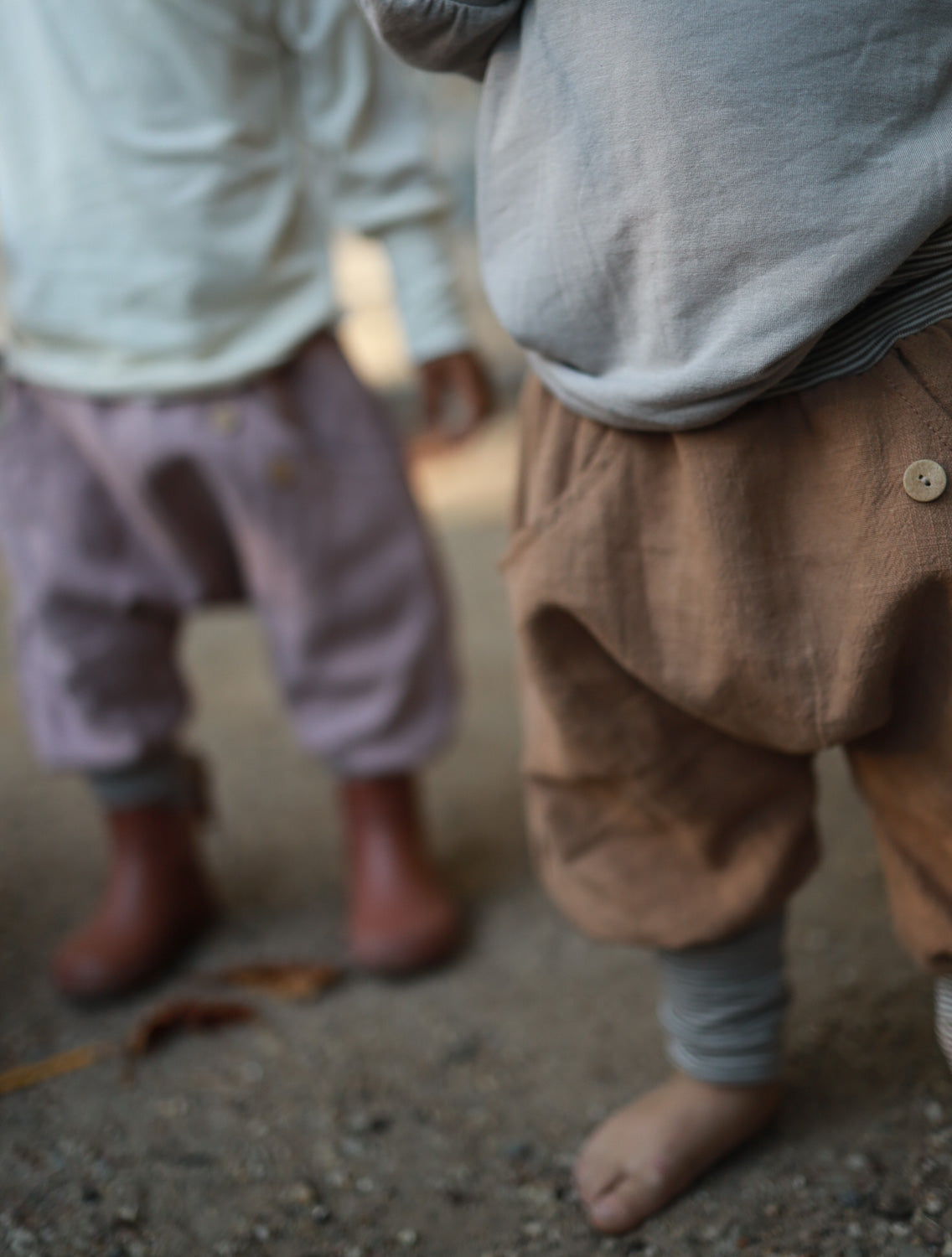 Zwei Kinder tragen bequeme petit cochon Knickerbocker aus Leinen in Braun und Altrosa mit Knopfdetails