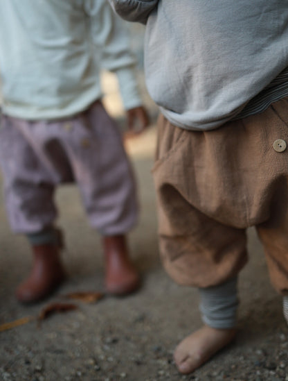Zwei Kinder tragen bequeme petit cochon Knickerbocker aus Leinen in Braun und Altrosa mit Knopfdetails