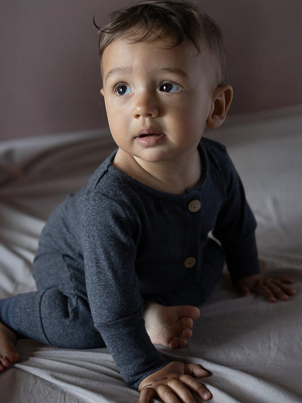 petit cochon Mini Overall aus dunkelgrauem, meliertem Feinstrick-Jersey an einem sitzenden Baby