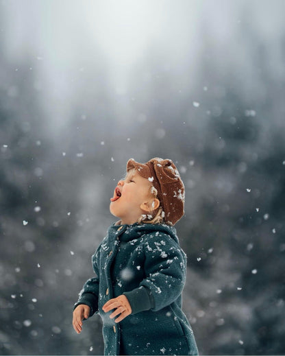 Kind in petit cochon Wollwalk-Wichteljacke mit Bio-Jersey-Futter beim Spielen im Schneefall