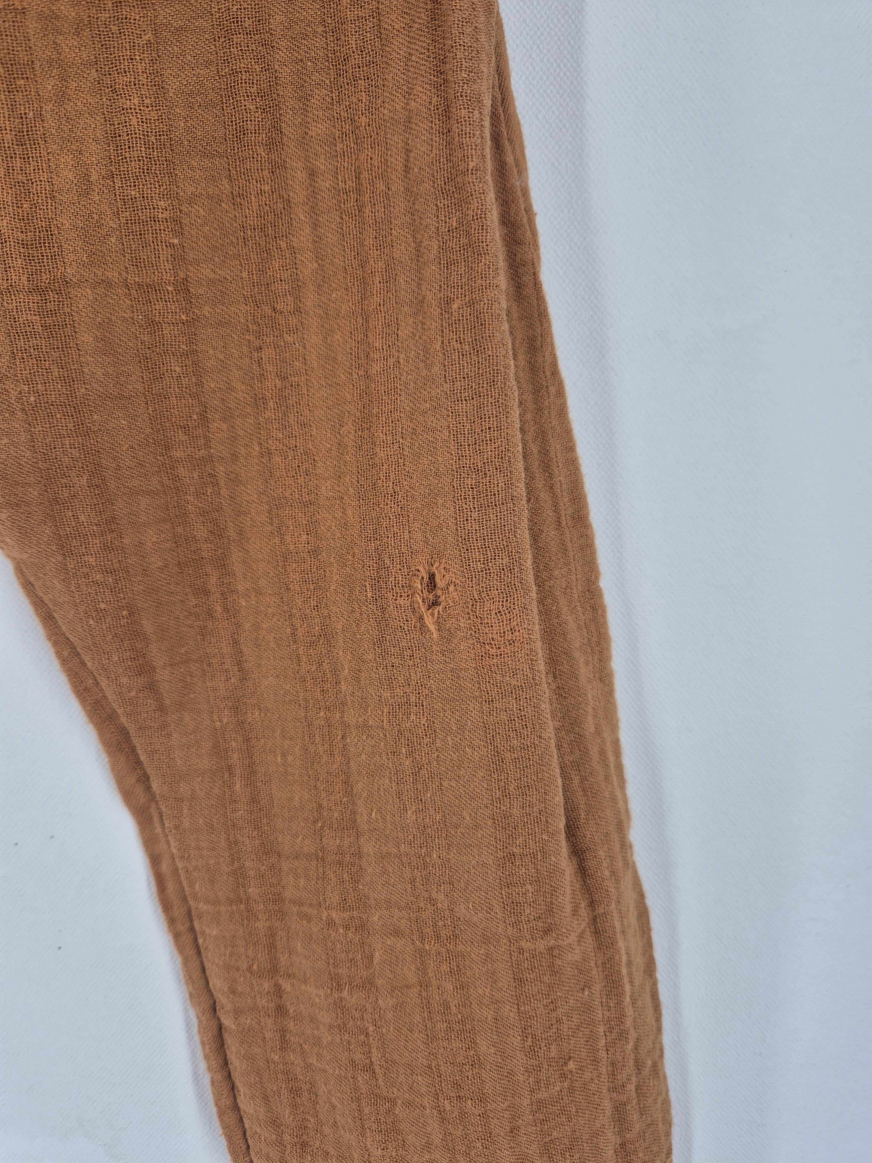 Sommerknicker Bio Musselin Sahara Gr. 3Y, ein locker gewebter Stoff mit kleinem Loch in der Mitte, vor weißem Hintergrund drapiert.
