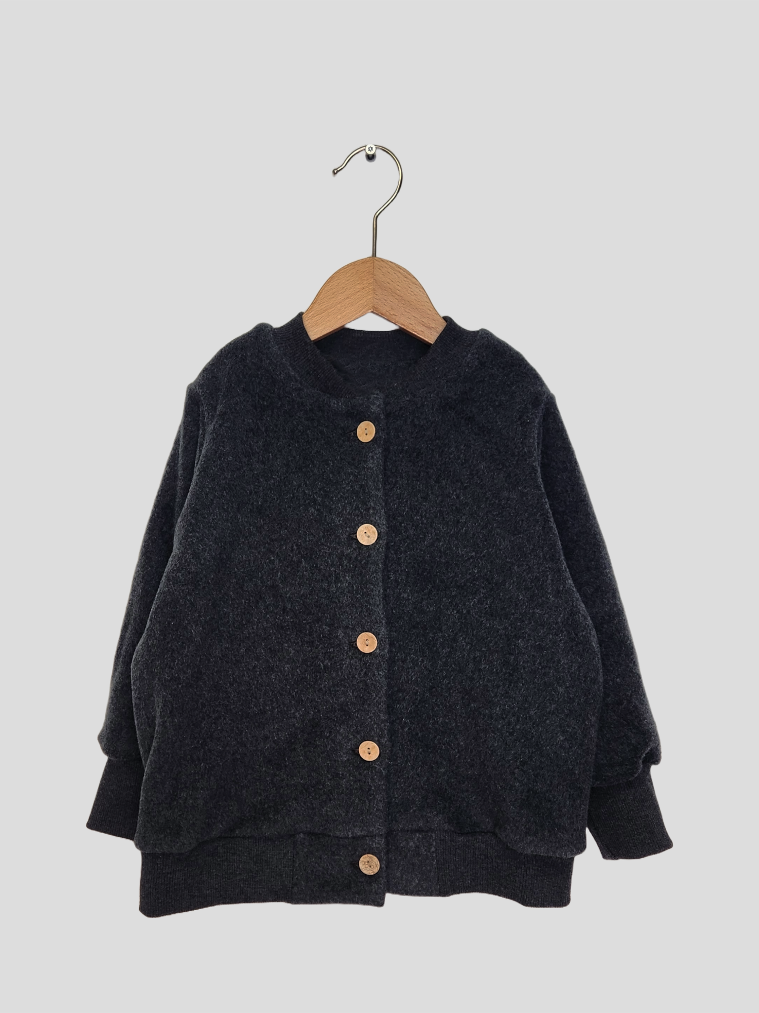 Bomberjacke Bio-Plüsch - Ruß auf einem Holzschwinger, zeigt weiche, langlebige Baumwollstruktur mit Krempelbündchen und versteckten Seitentaschen, ideal als Übergangsjacke.