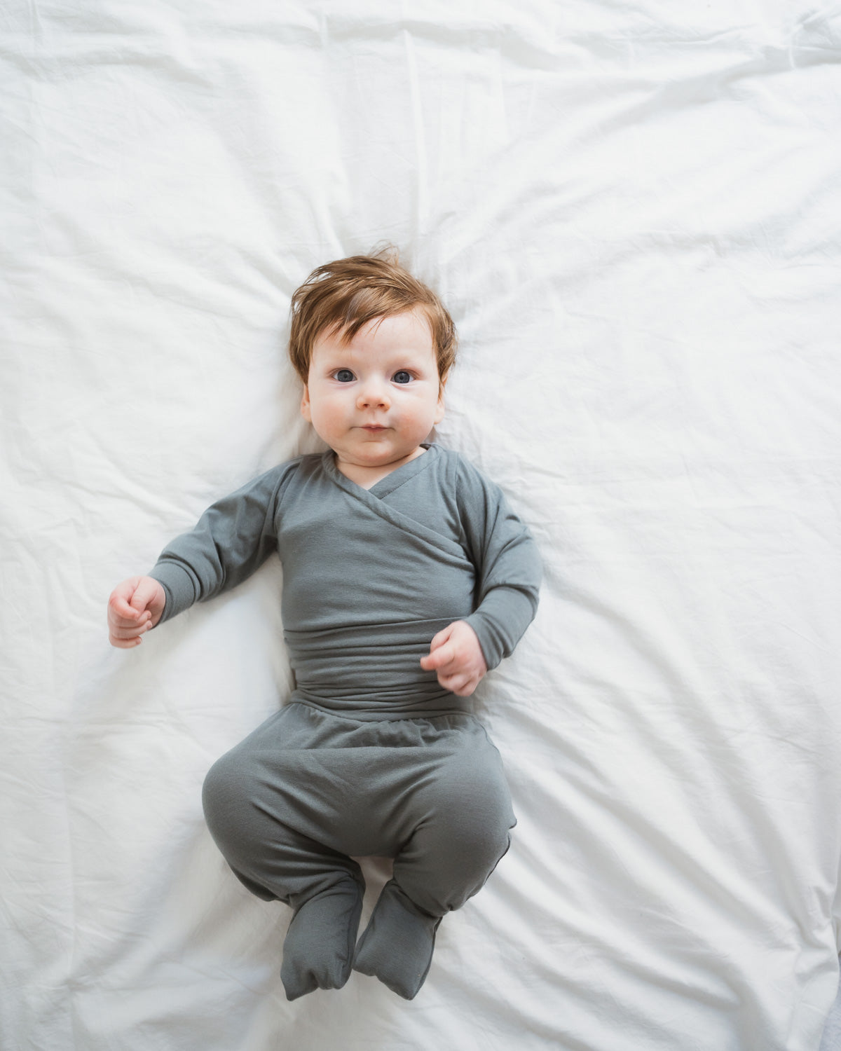 Baby trägt Babyknicker Kaschmir-Mix mit Klappbündchen auf weißem Untergrund, ideal für Komfort und Wärme, passend zum Loopbody für Neugeborene.