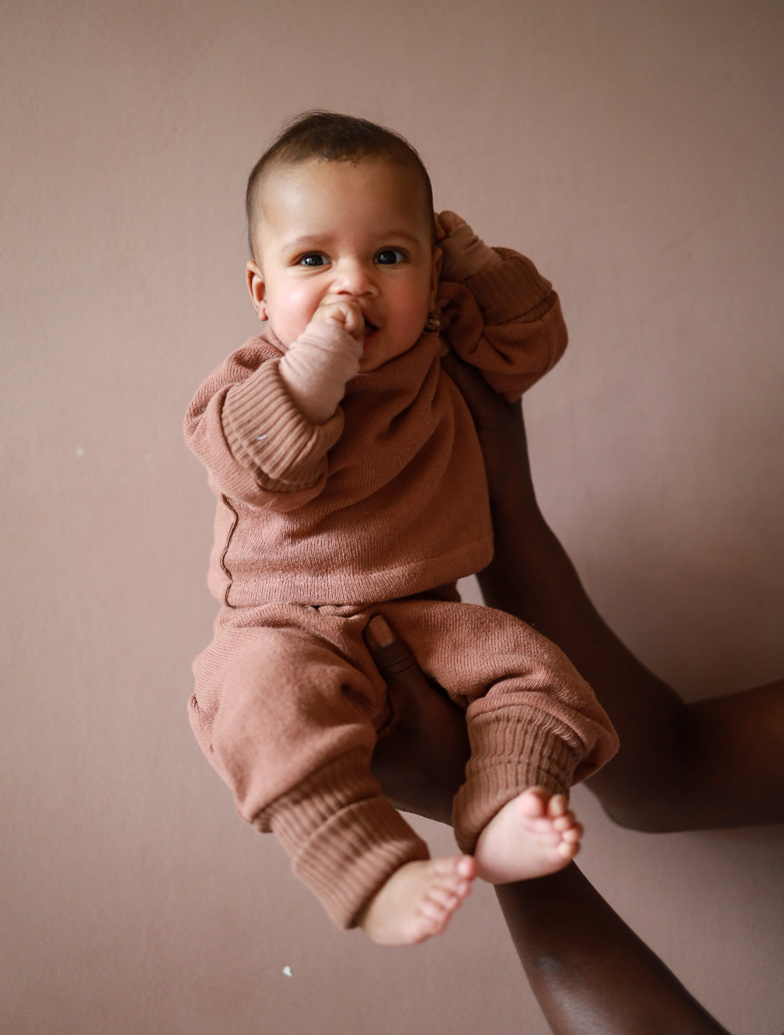 Babyfüße in Hand gehalten, Babyschlüttli Strick aus recycelter Baumwolle sichtbar, ideal für wachsende Babys, flauschig und unisex, hergestellt in Berlin. Baby Set Strick. Erstausstattung Babys. Perfekte Baby Geschenke.