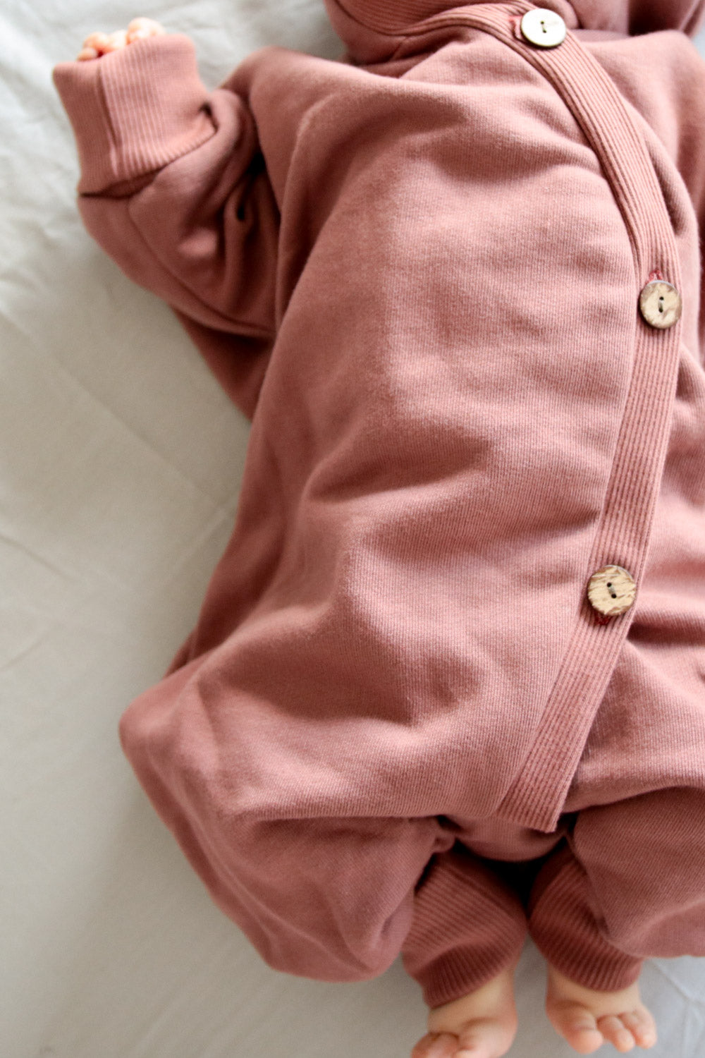 Kuschelanzug Bio-Sweat - Zimt: Pinker Overall mit Knöpfen, aus weichem Bio-Baumwoll-Sweat, Wichtelkapuze, mitwachsend durch Krempelbündchen an Armen und Beinen. Perfekt für Babys, drinnen und draußen.