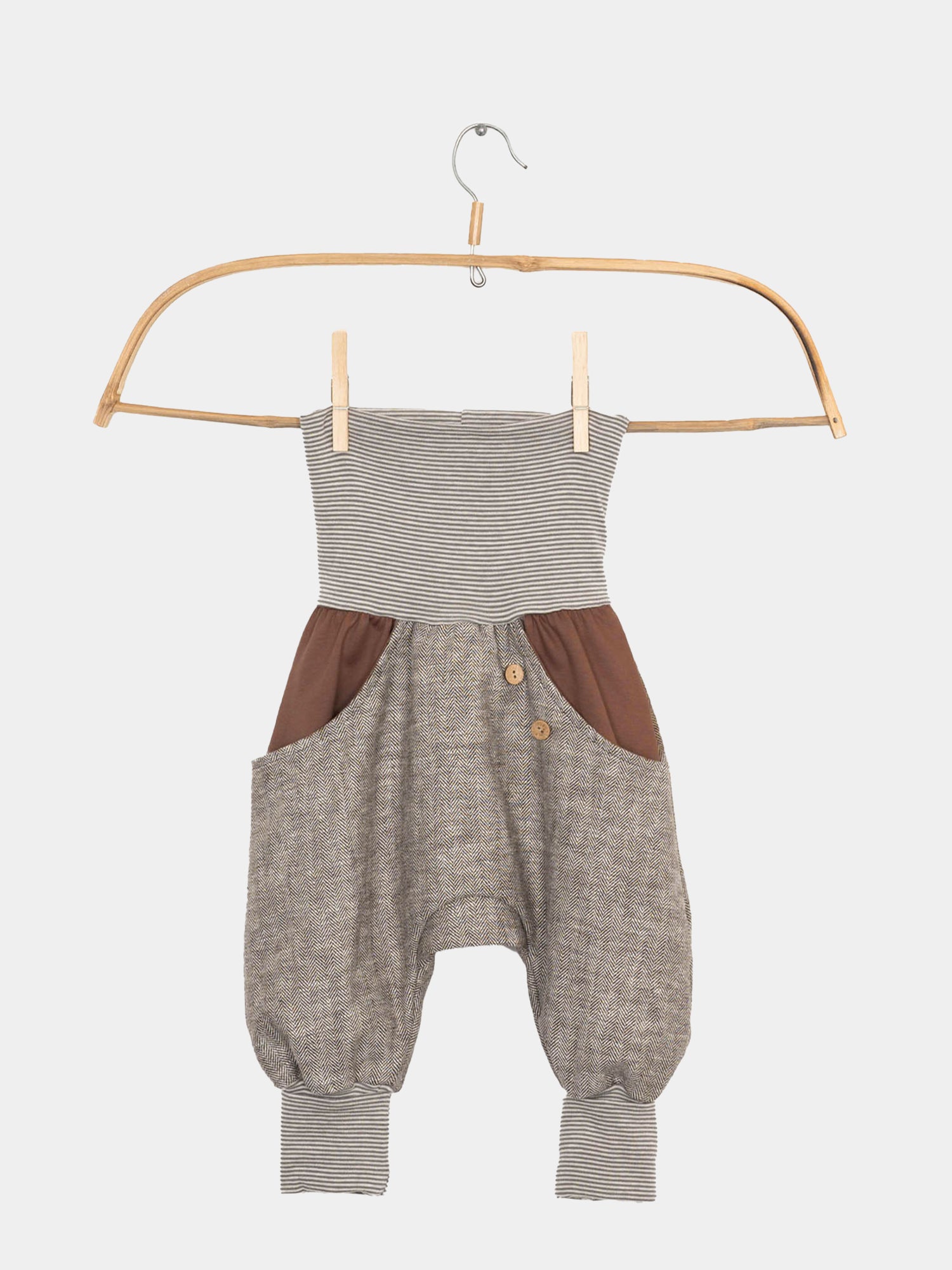 Knickerbocker Fischgrat - Schoko: Eine Babyhose aus robustem Fischgratstoff, bequem geschnitten mit elastischen Bündchen und großer Kängurutasche, auf einem Kleiderbügel präsentiert. Perfekt für jede Jahreszeit.