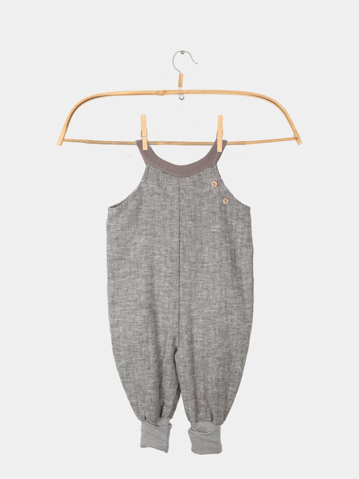 Schlupflatzhose aus Fischgrat auf einem Kleiderbügel, Sie zeigt das robuste Leinen-Baumwoll-Mix-Material und die umkrempelbaren Jerseybündchen, ideal für Kinderbewegungen.