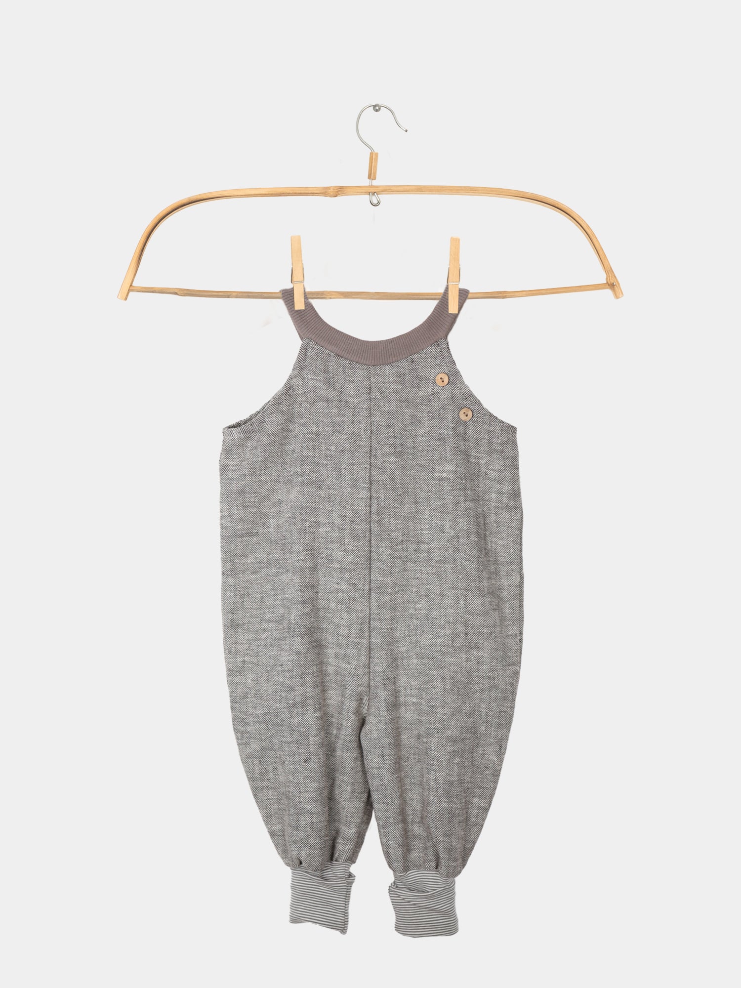 Schlupflatzhose aus Fischgrat auf einem Kleiderbügel, Sie zeigt das robuste Leinen-Baumwoll-Mix-Material und die umkrempelbaren Jerseybündchen, ideal für Kinderbewegungen.