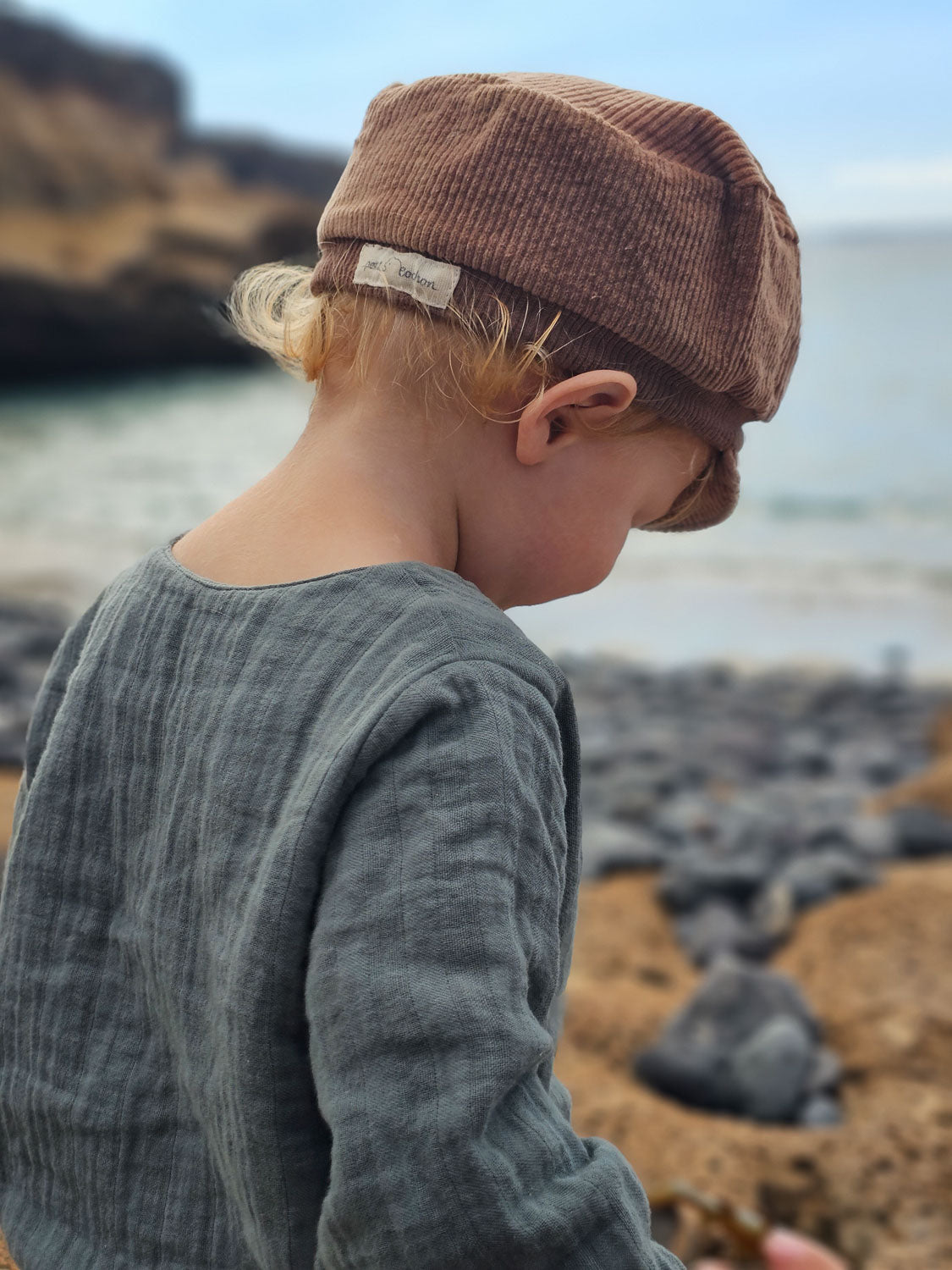 Kind am Felsenstrand trägt Hemdchen Bio-Musselin - Taube aus 100% Bio-Baumwolle, ideal für Alltag und festliche Anlässe, handgefertigt in Berlin. nachhaltige Kinderkleidung