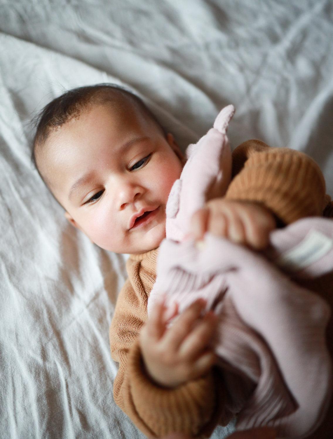 Ein Baby hält ein Schnuffel-Schweinchen - Puder aus recycelter Baumwolle, ideal als kuscheliger Begleiter oder Geschenk zur Geburt
