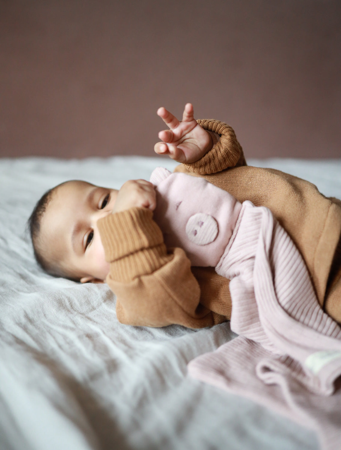 Schnuffel-Schweinchen - Puder: Ein Baby hält ein kuscheliges Schweinchen aus recycelter Baumwolle, ideal als beruhigender Begleiter oder Geschenk für Neugeborene.