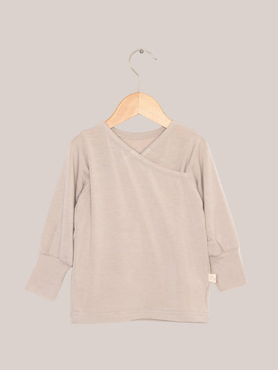 Cashmere-blend wrap top – Sand on a wooden hanger, showing its soft, stretchy texture and roll-up cuffs. Ideal as a top or undershirt.
