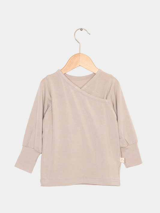 Wickelshirt aus Kaschmir-Mix - Sand auf Holzkleiderbügel, zeigt weiche, elastische Struktur und krempelbare Bündchen. Ideal als Shirt oder Unterhemd.